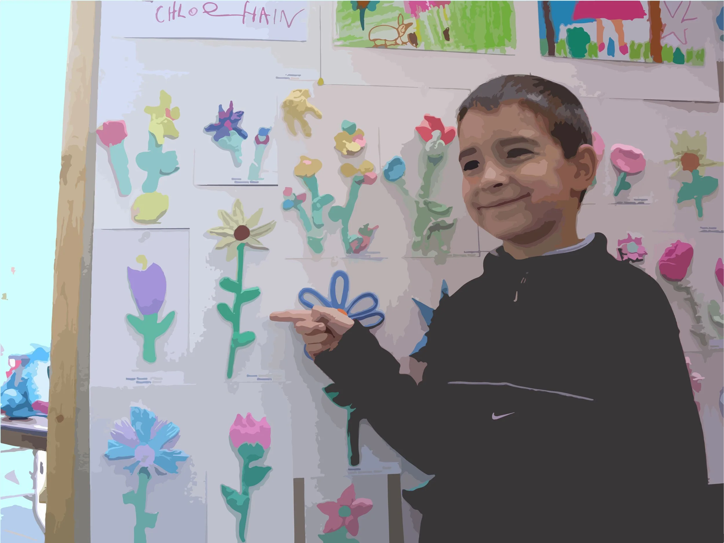 image of child pointing to artwork of a flower on a board of other artwork of flowers