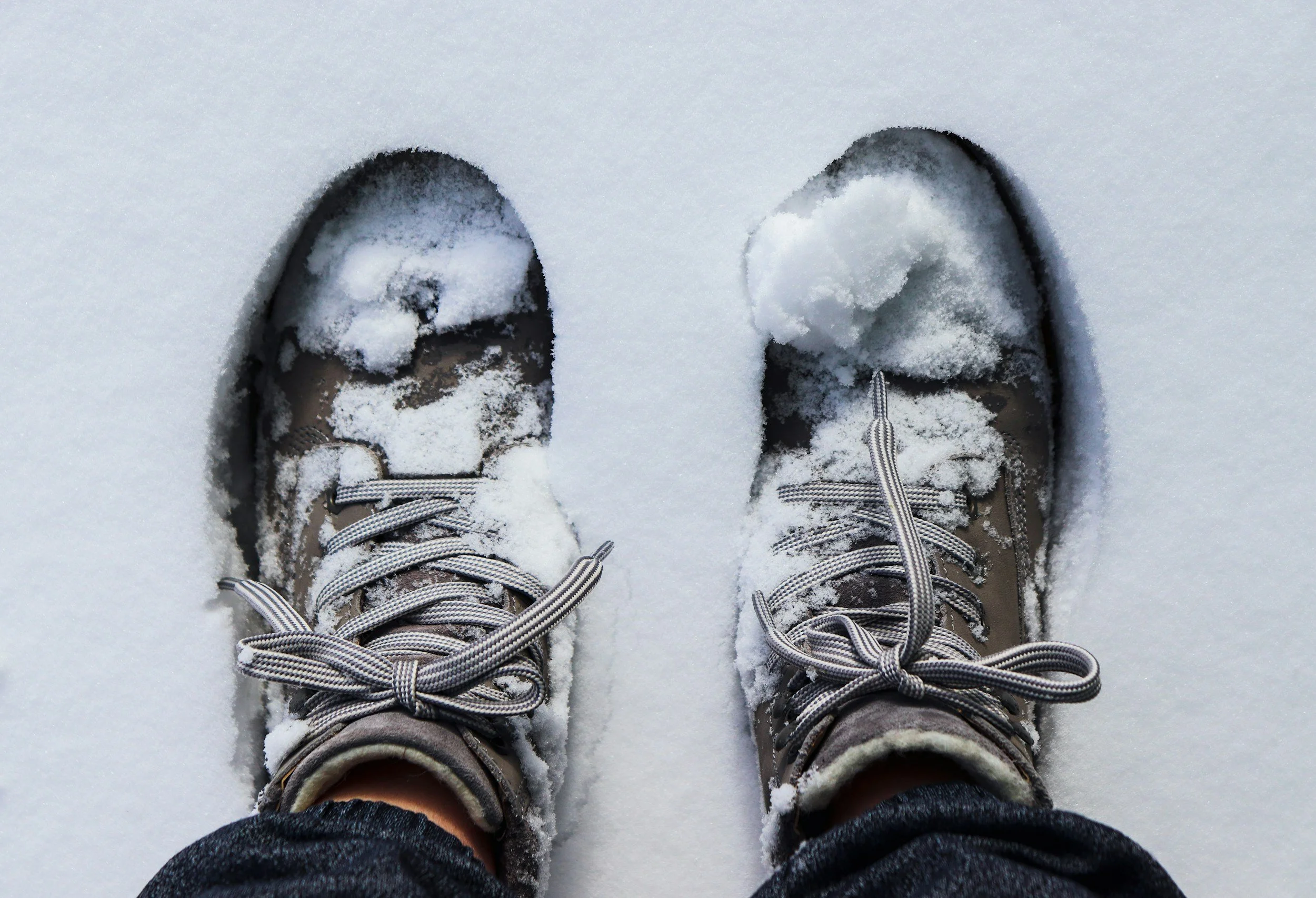 A pair of boots standing in the snow.