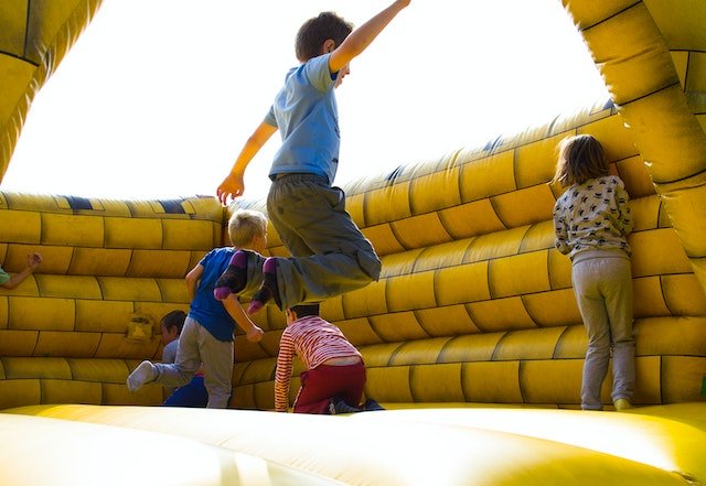 Children jumping around in bounce house.