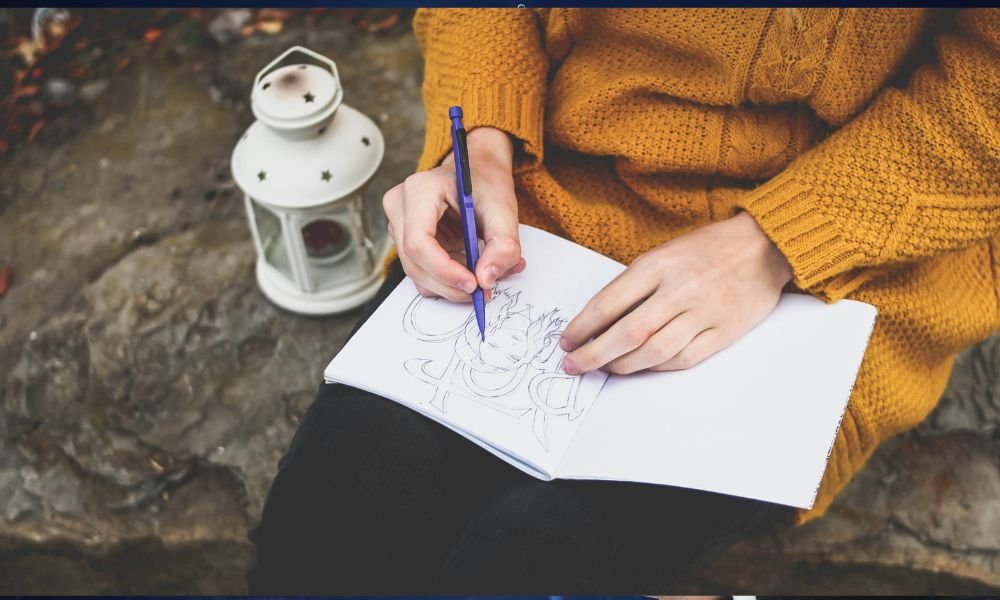 person-drawing-on-sketch-book-near-white-lantern