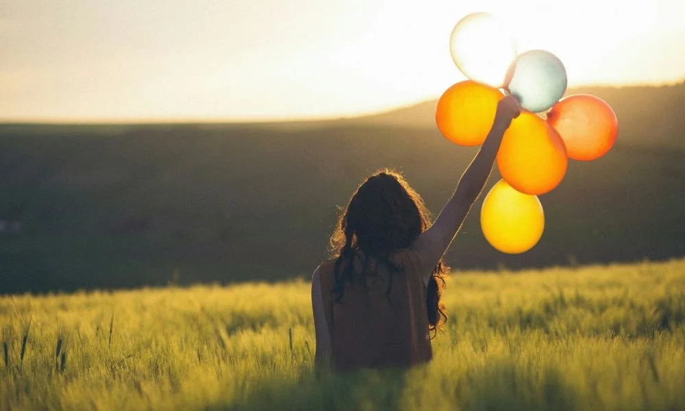 unknown-person-holding-balloons-outdoors