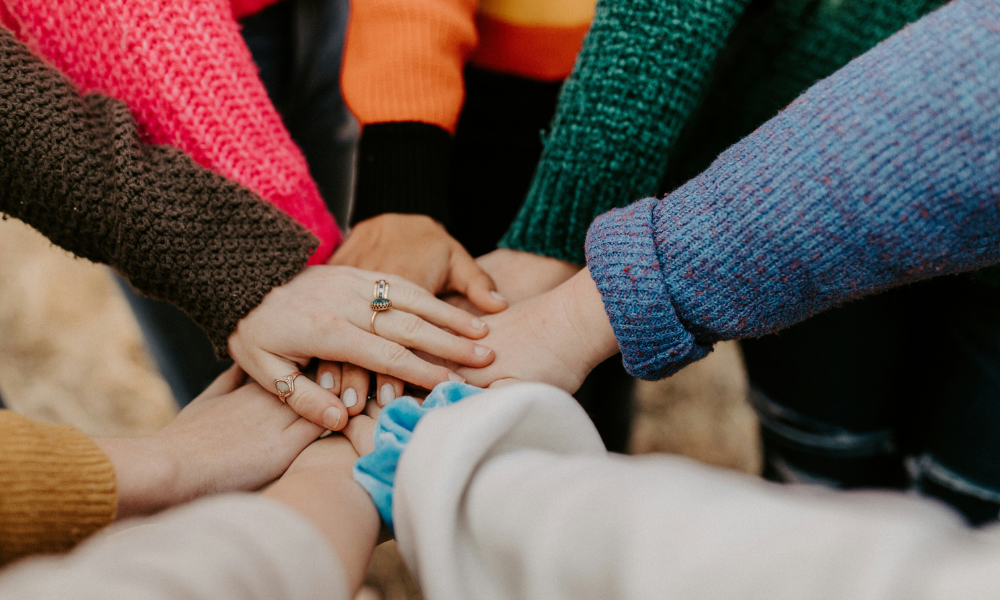 group-stacking-hands-in-colorful-sweaters
