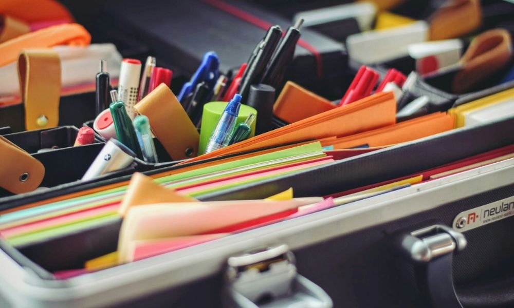 An organized collection of colorful stationery in a briefcase, featuring pens, pencils, highlighters, and stacked folders, conveying productivity.
