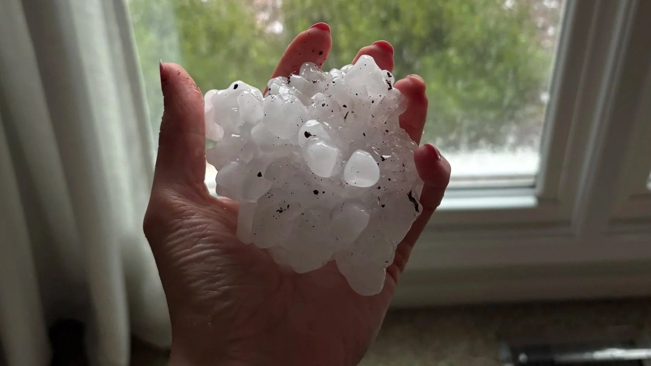 Picture of softball-size hail in palm of a hand.