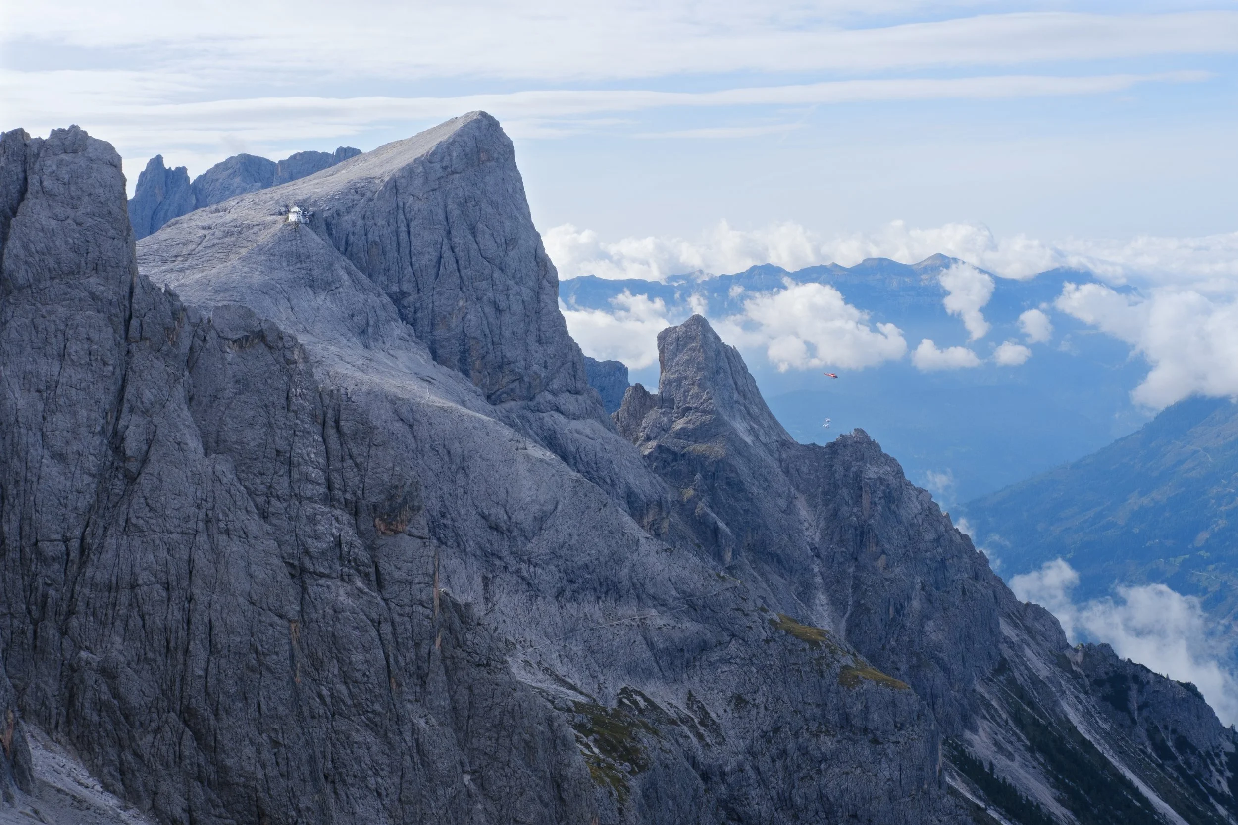 A mountain in the Italian Dolomites with a helicopter ferrying supplies from a mountain refugio.