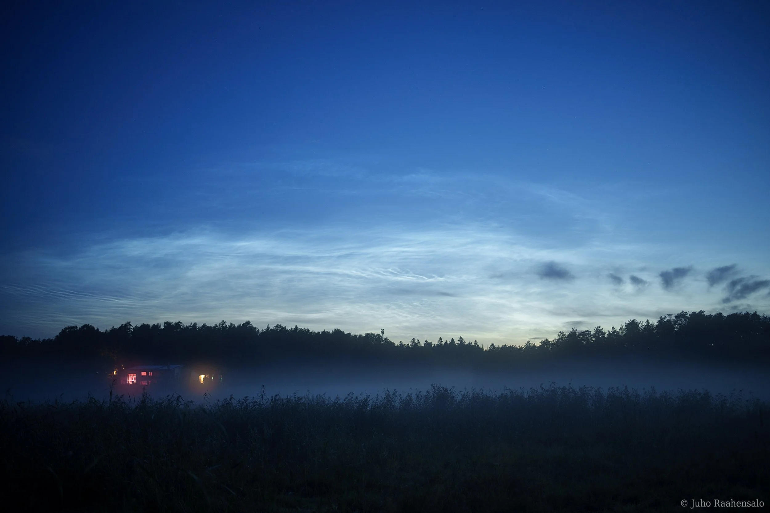 Noctilucent clouds over misty field
