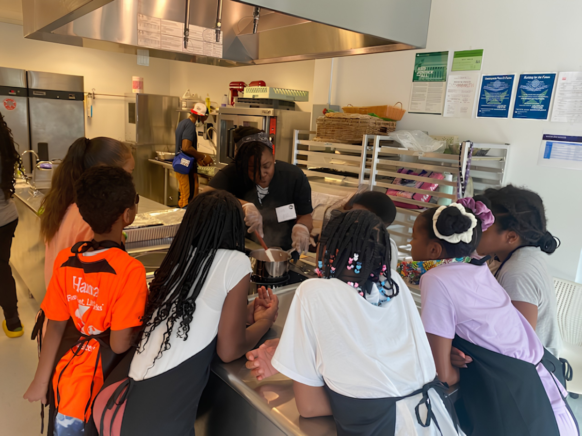 Children learning hands-on cooking skills with Chef Mai at Say Grace Children's Culinary Academy.