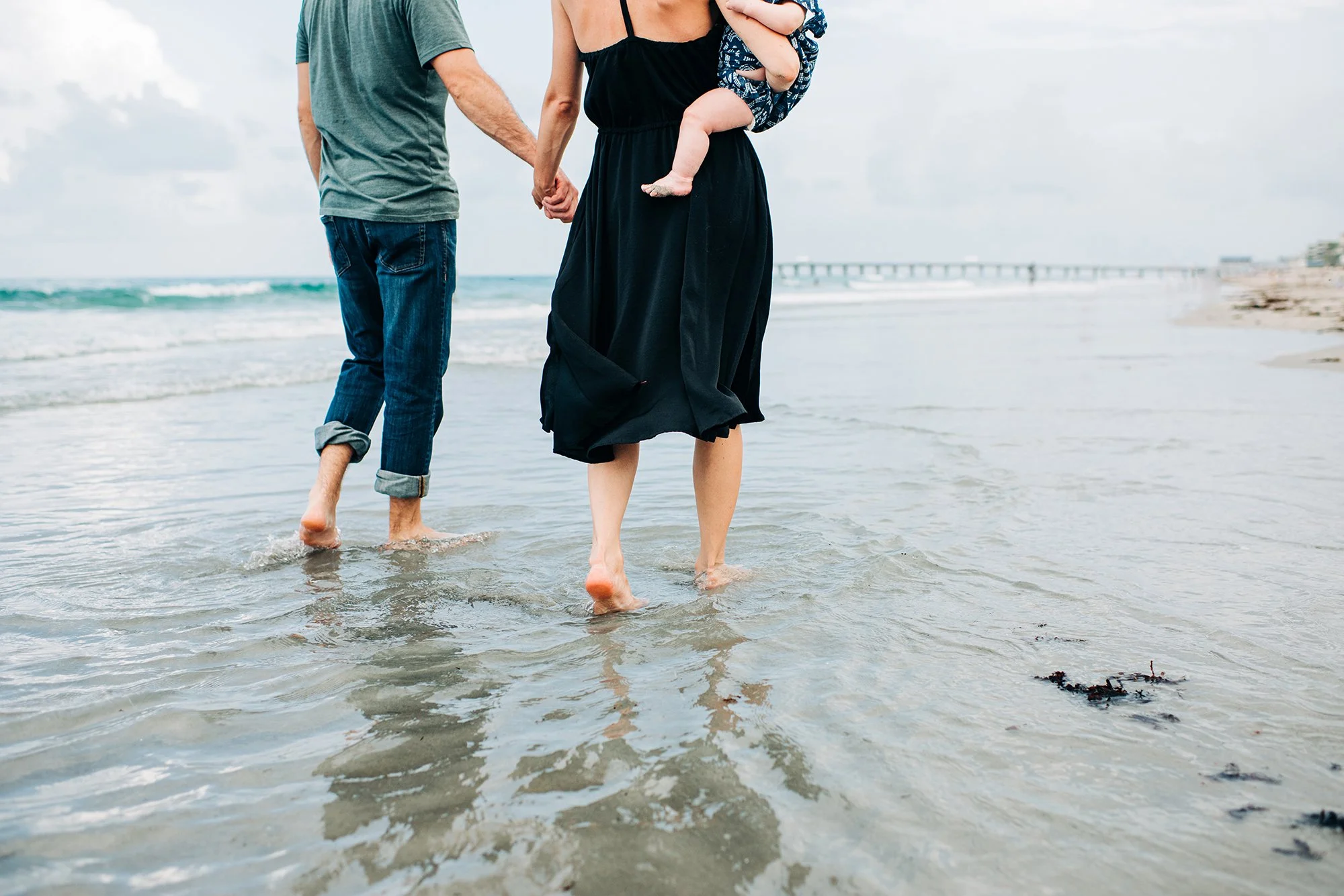 mother father and baby walk on shoreline Juno Beach FL