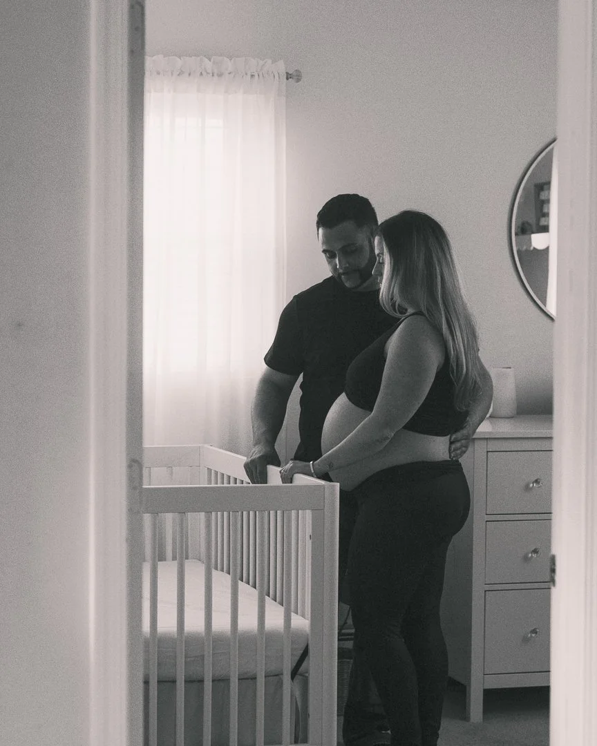 A couple preparing or counting on a changing table in a nursery, with a crib visible in the foreground.