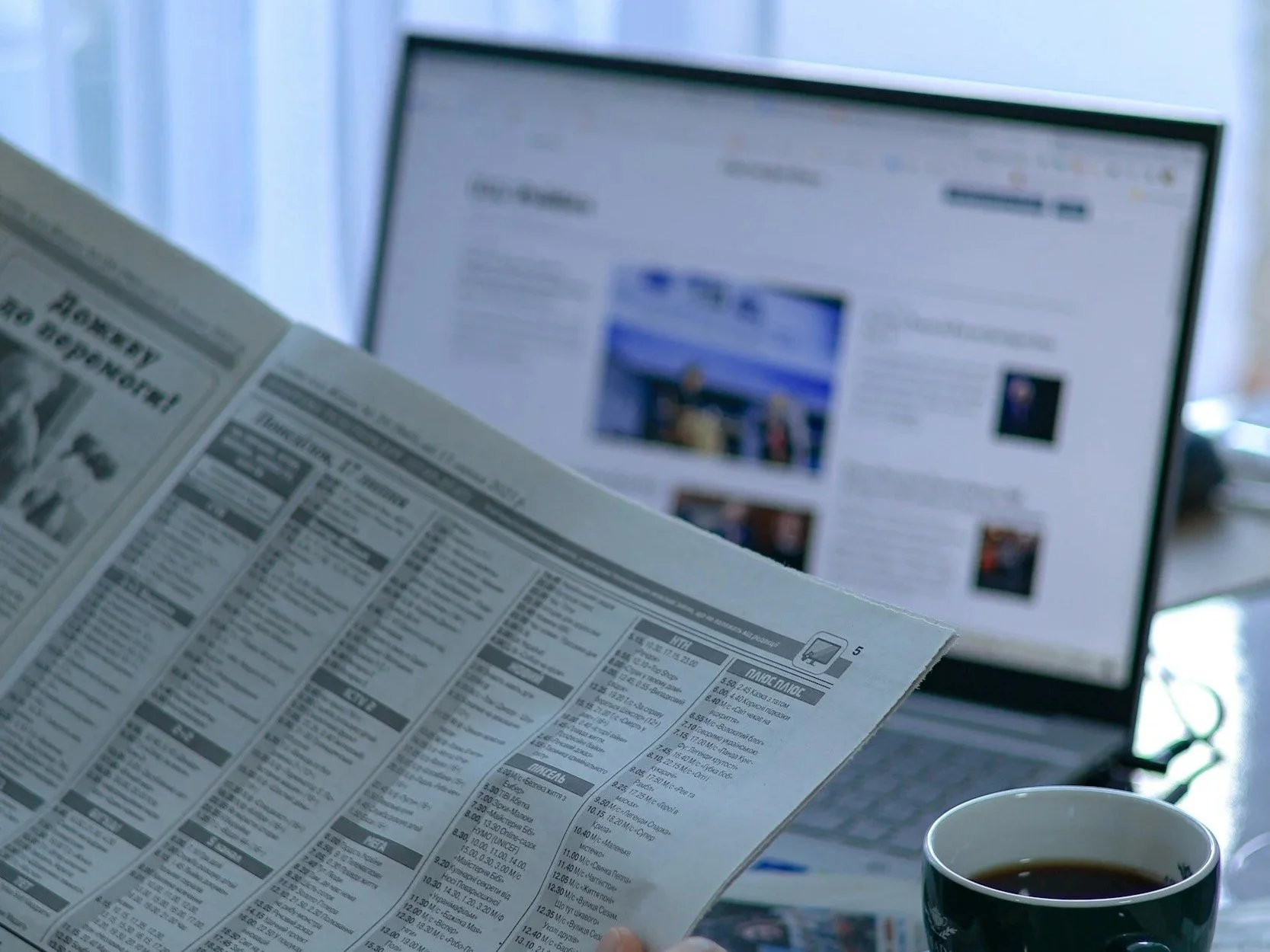 Newspaper beside an open laptop and a mug of coffee on a desk, representing entertainment journalism, media coverage, industry news, and digital storytelling.
