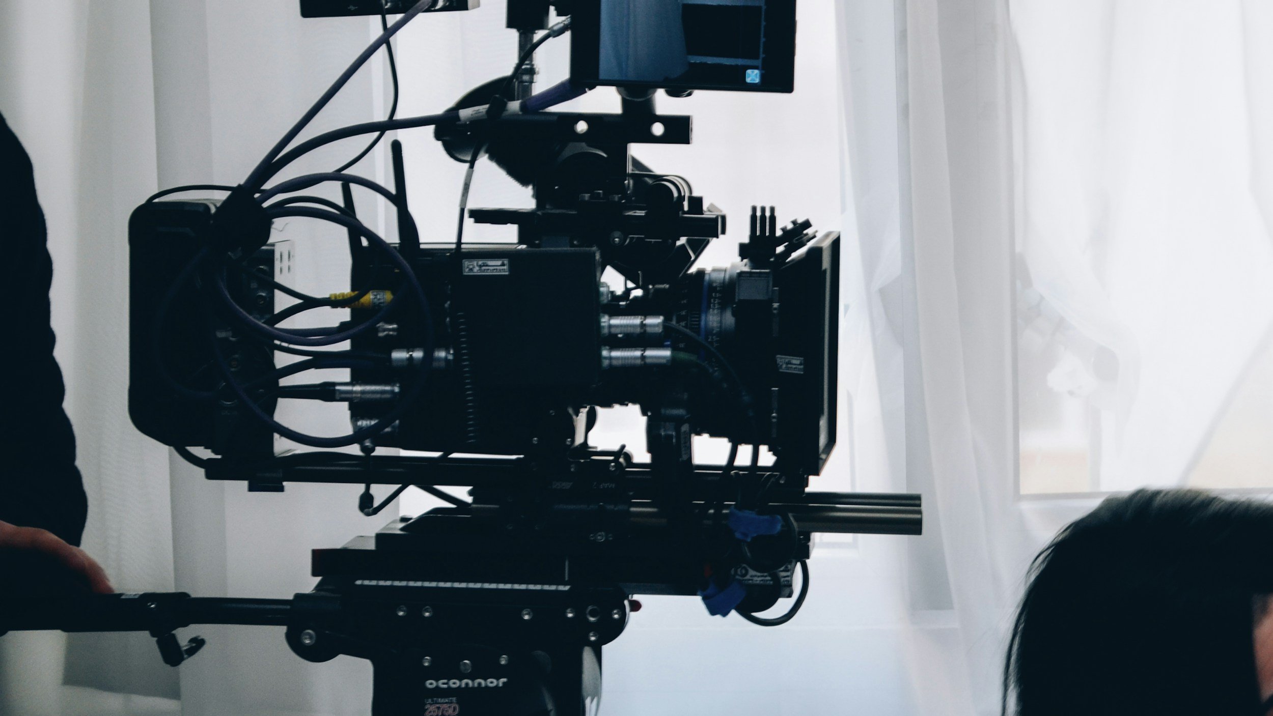 Professional film camera rig set up on a movie production set with lighting equipment and crew gear in the background.