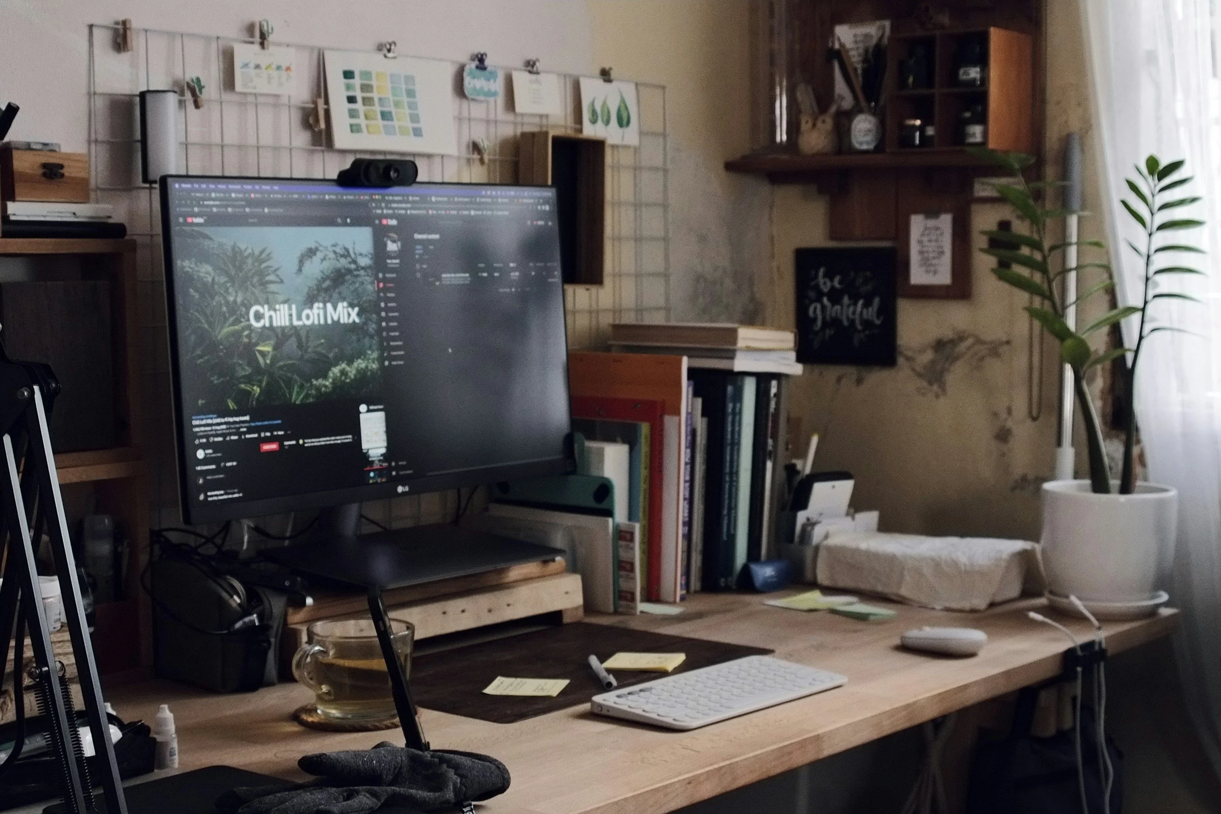 Creative workspace with a computer monitor, keyboard, desk accessories, and green plants.