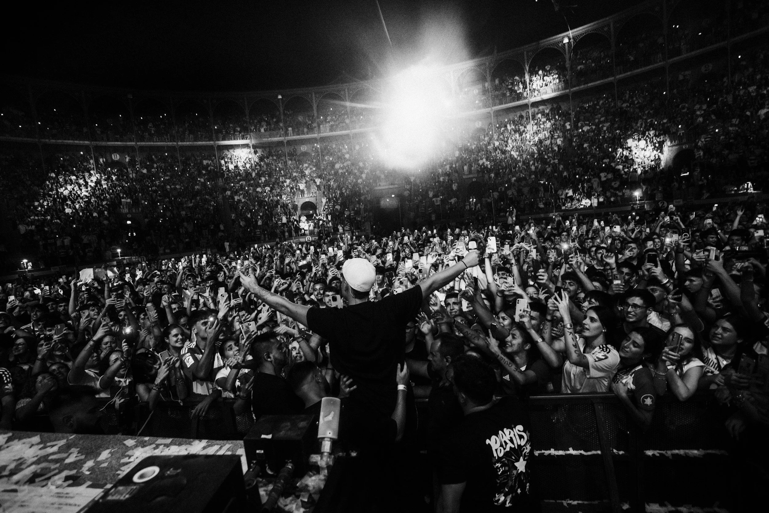 Black-and-white photograph of a crowd watching a man perform on stage, illustrating public admiration and celebrity culture.