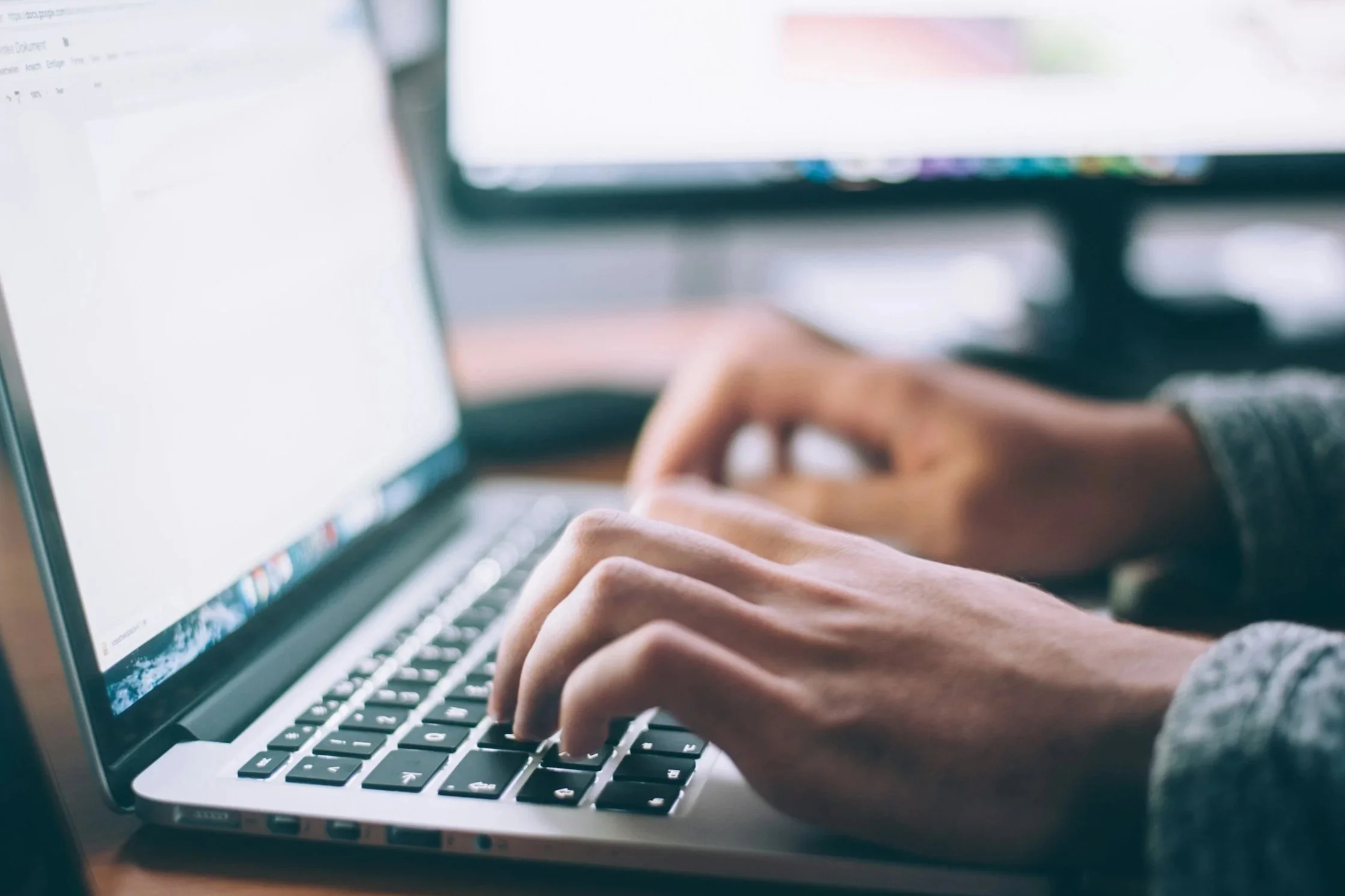 Close-up of a person working on a laptop at their desk.