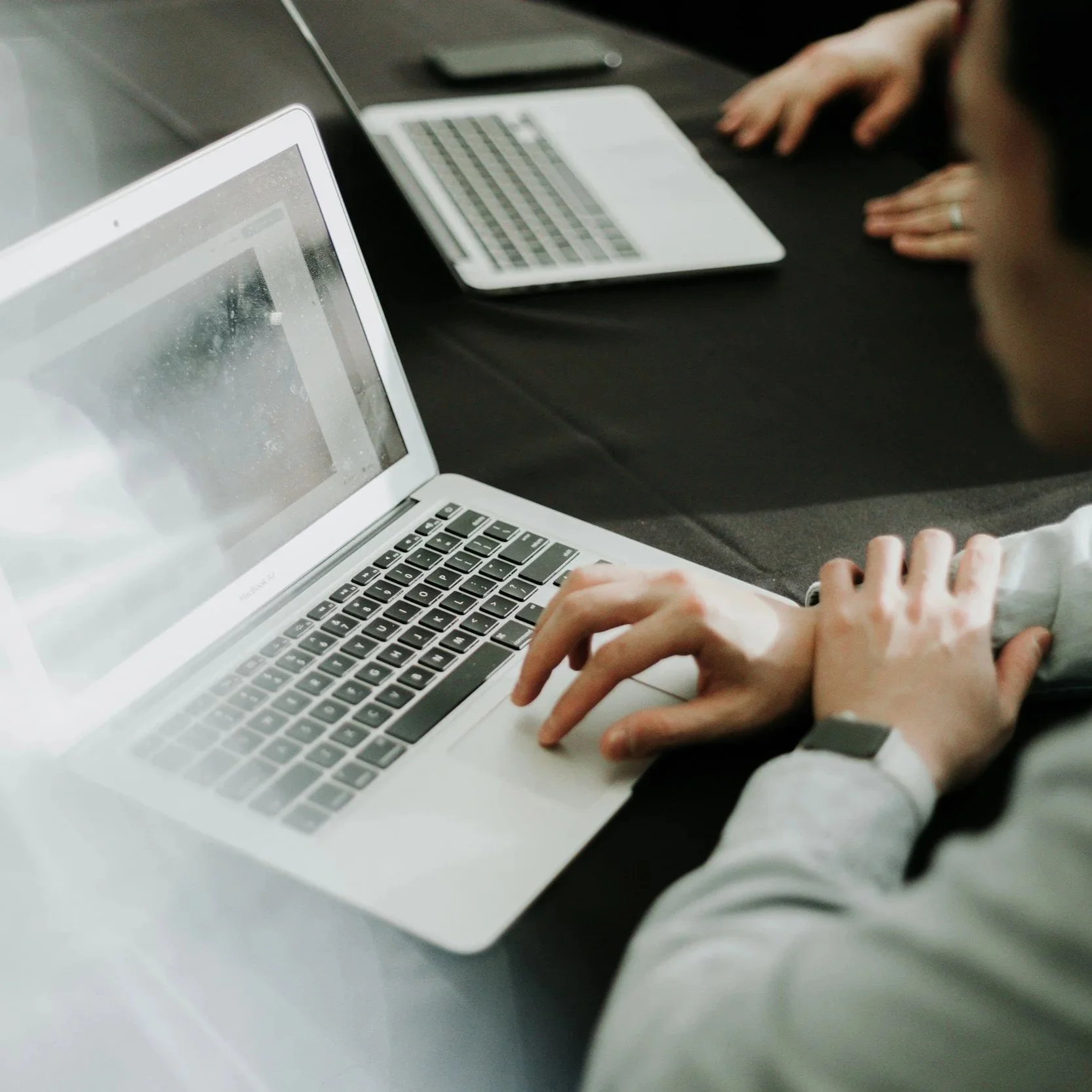 Person sitting at a desk working on a laptop, focused on writing or browsing, representing content creation or blogging.