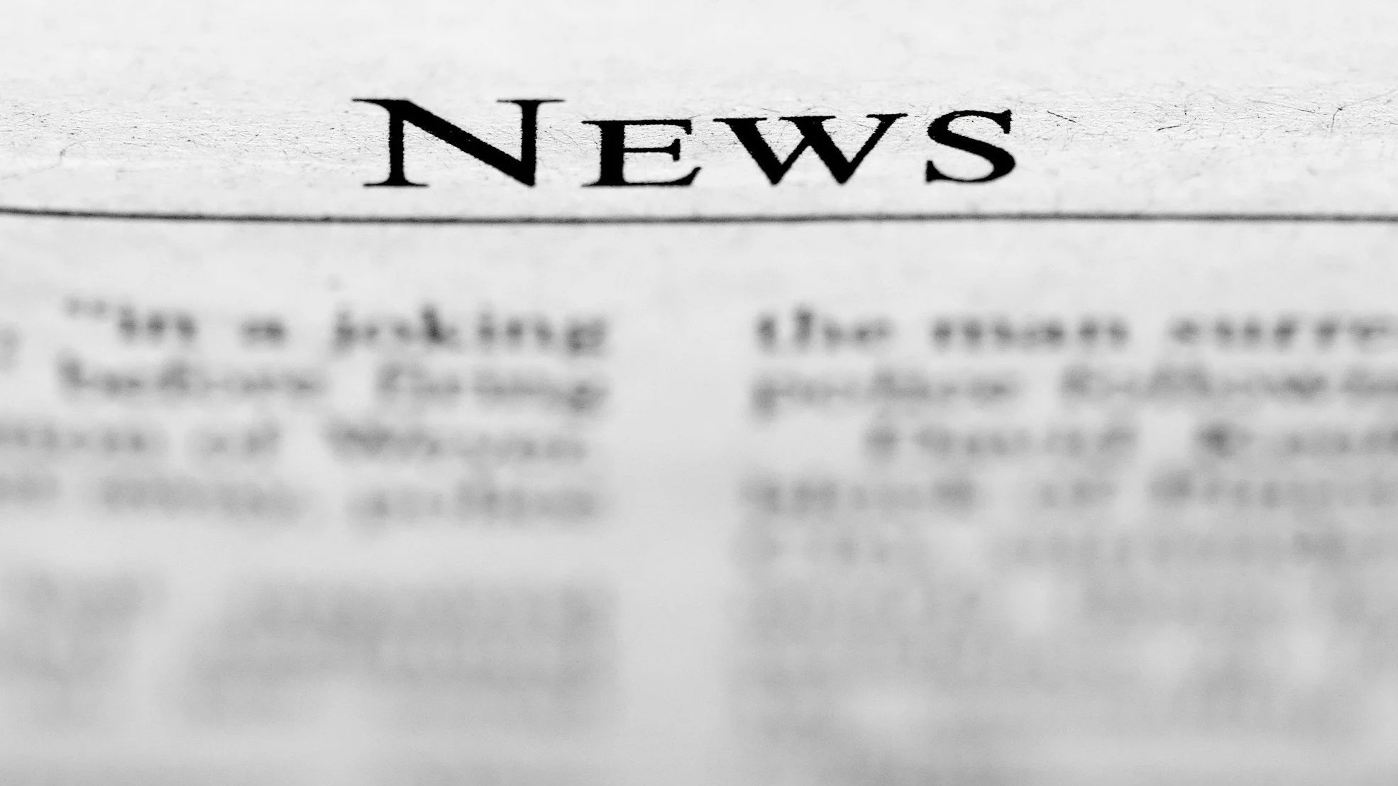 Close-up of a newspaper with the word ‘News’ in focus and the rest of the paper blurred, representing current events and journalism