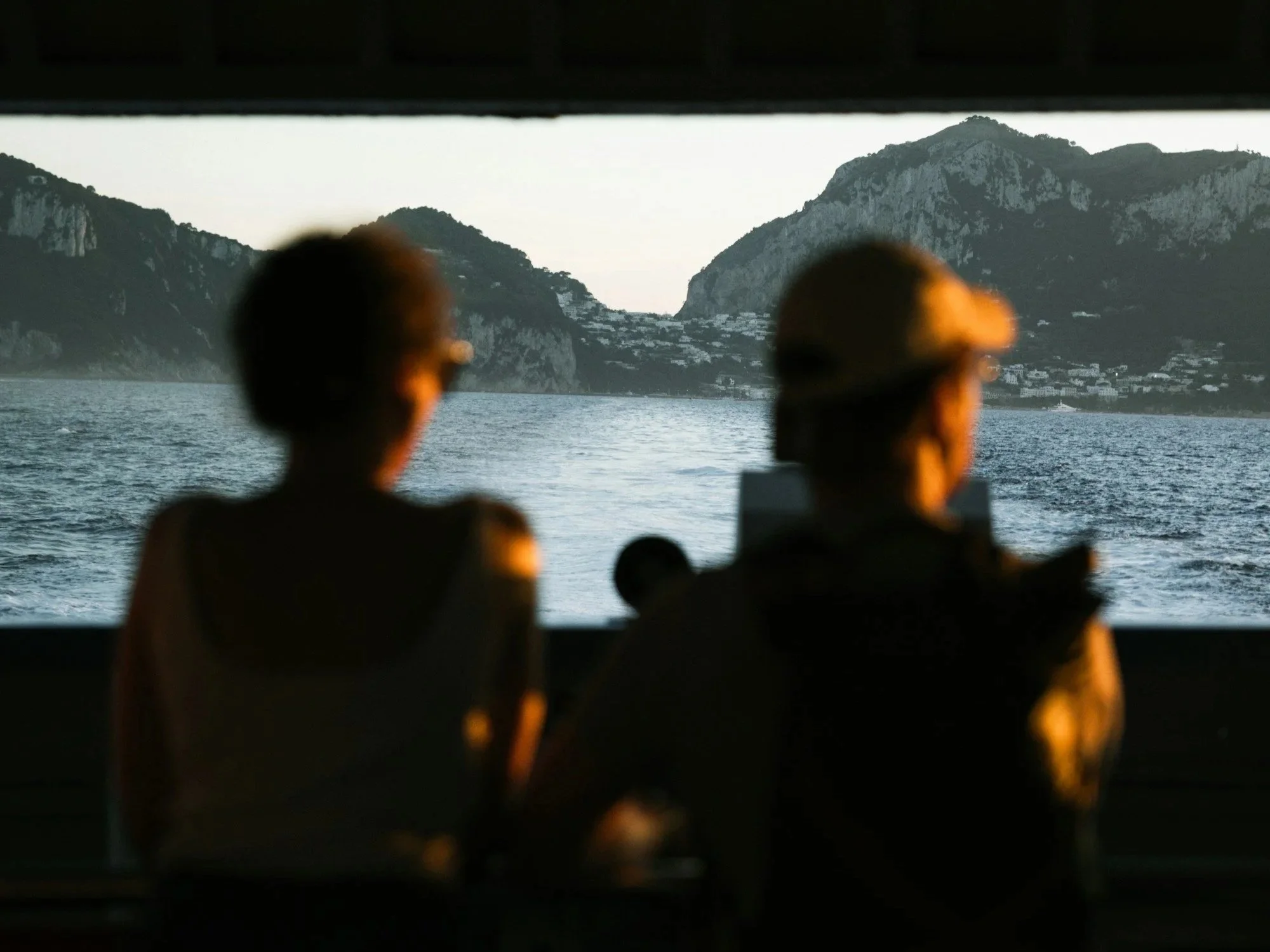 Two men viewed from behind in a dark theater as cameras record a screen, evoking public image, media scrutiny, and reputation.