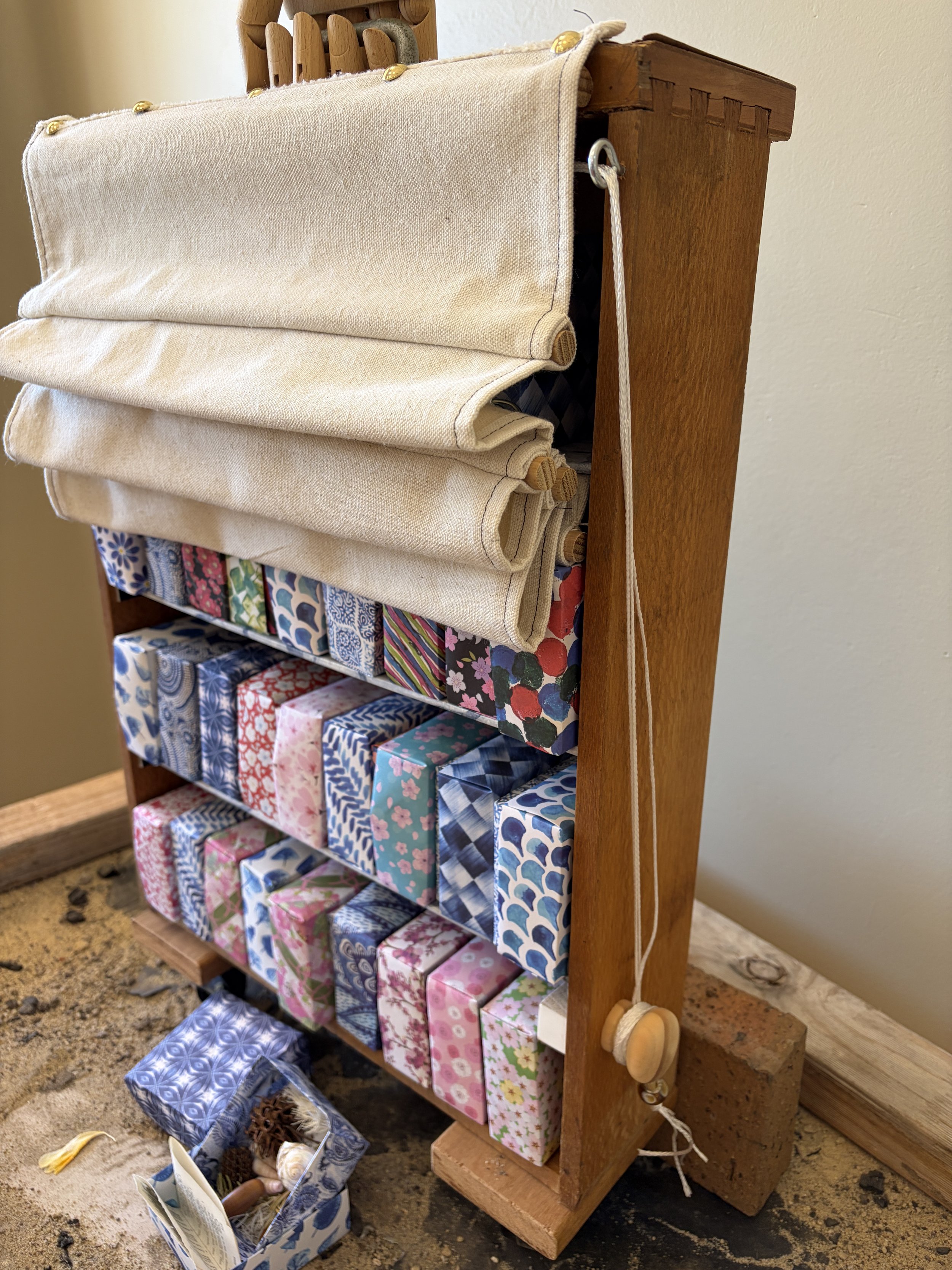 This sculpture explores the idea of prayer as something gathered, held and carried. Small boxes fill an old wooden drawer that has become a cabinet, suggesting a collection of words, memories and petitions accumulated over time. A canvas covering can