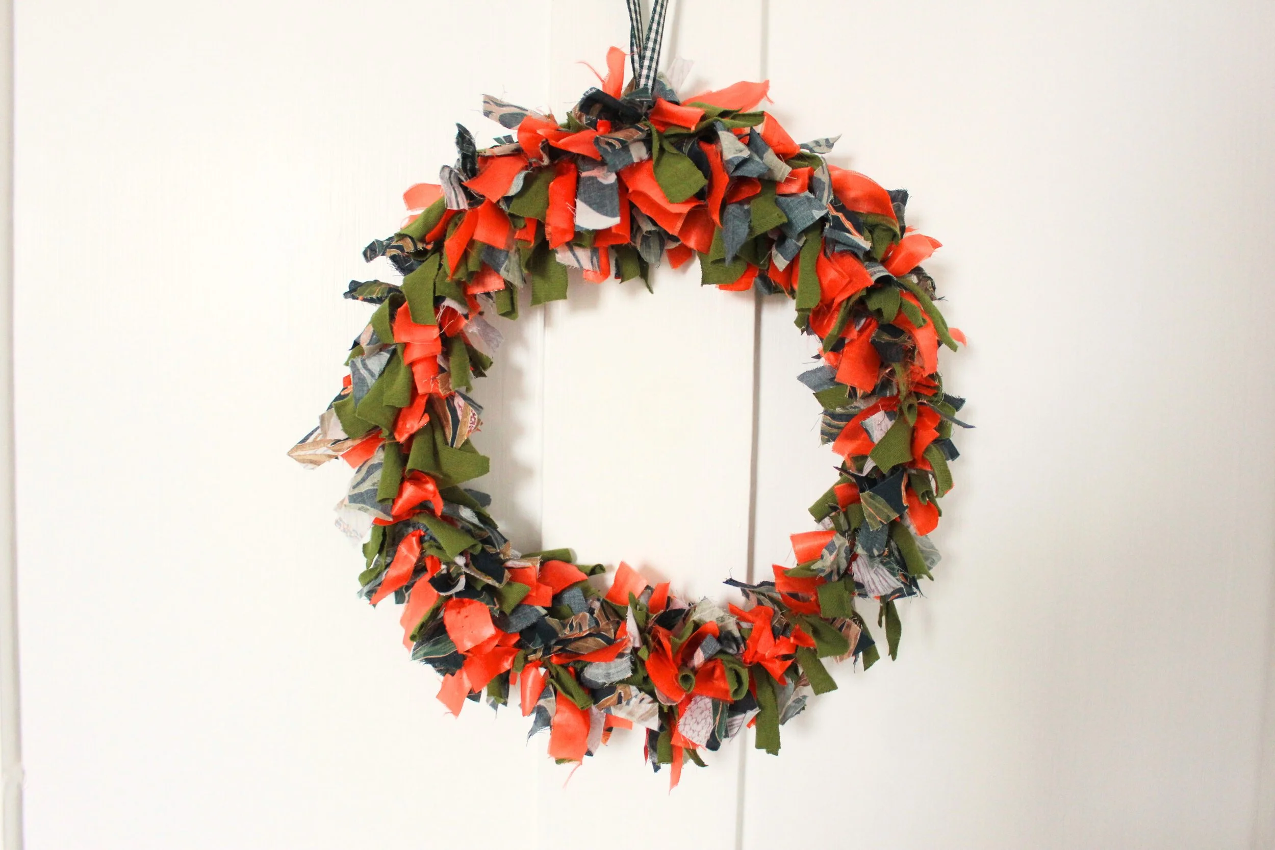 Photo of a colourful scrap fabric wreath hanging on a white door
