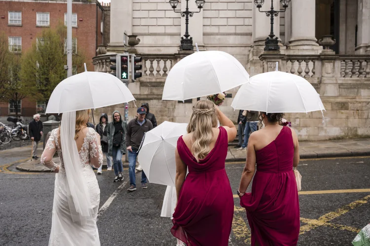 Bride and bridesmaids under white umbrellas outside Dublin City Hall