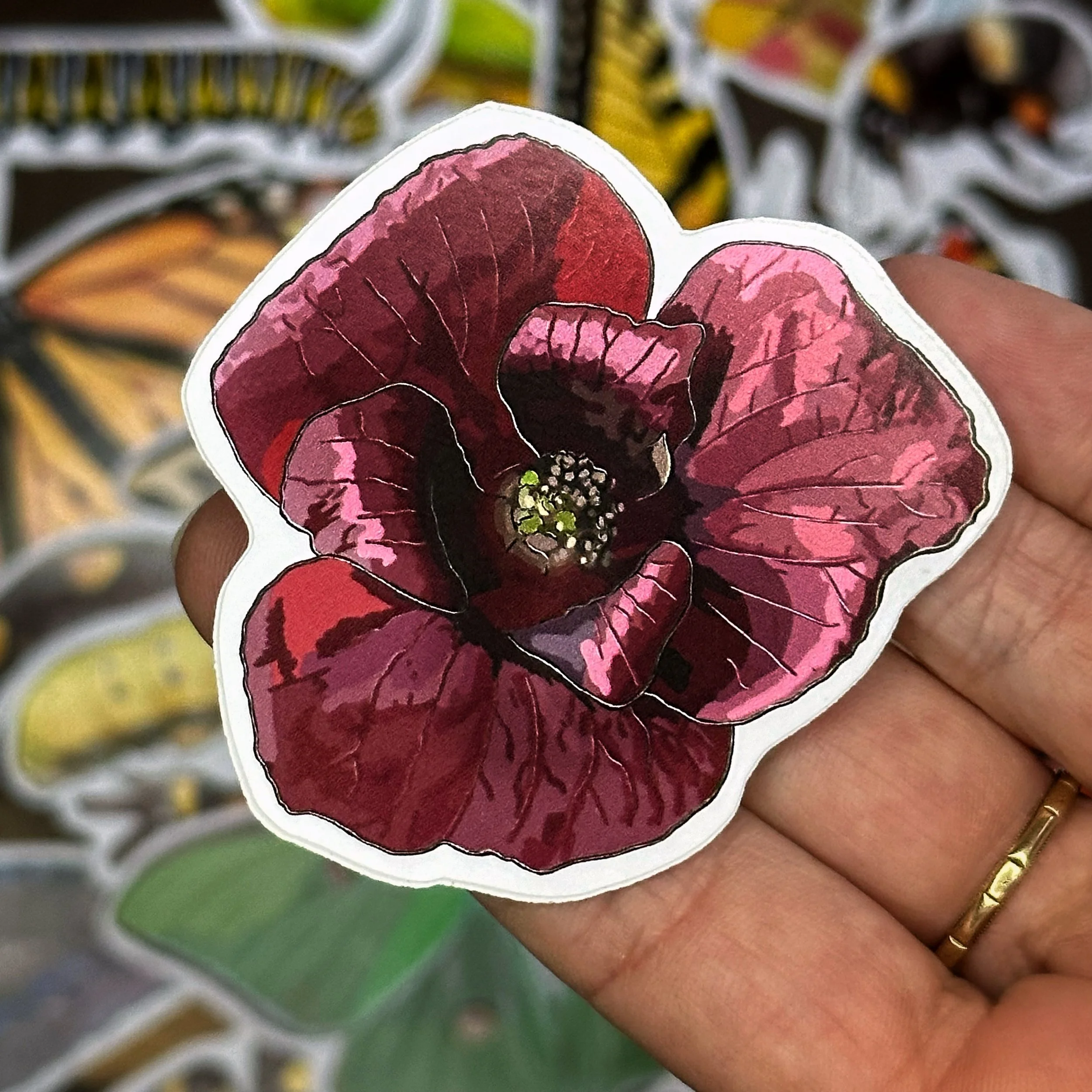 Pawpaw flower sticker held above a pile of other stickers