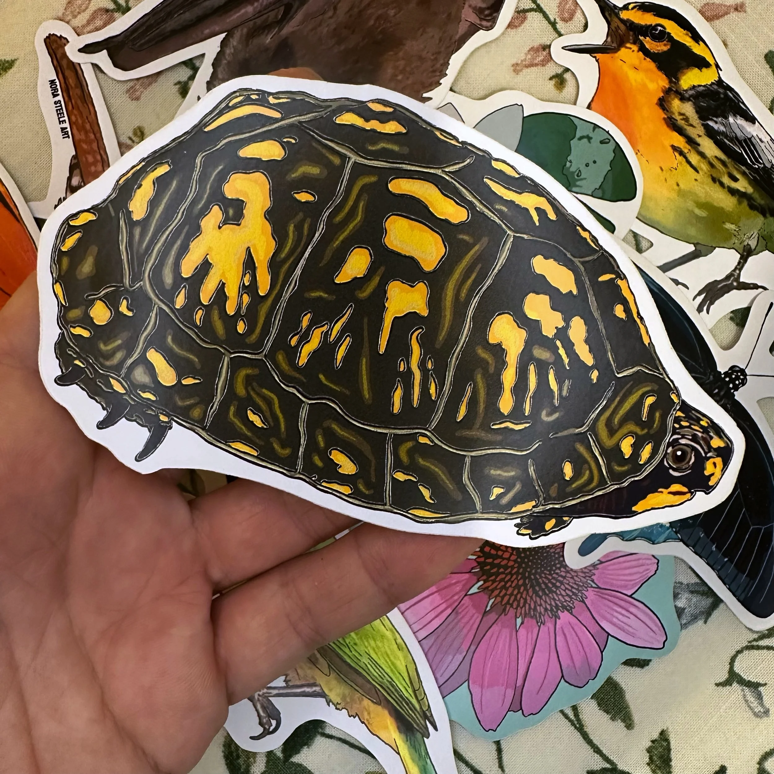 Easter box turtle sticker held above a pile of other stickers