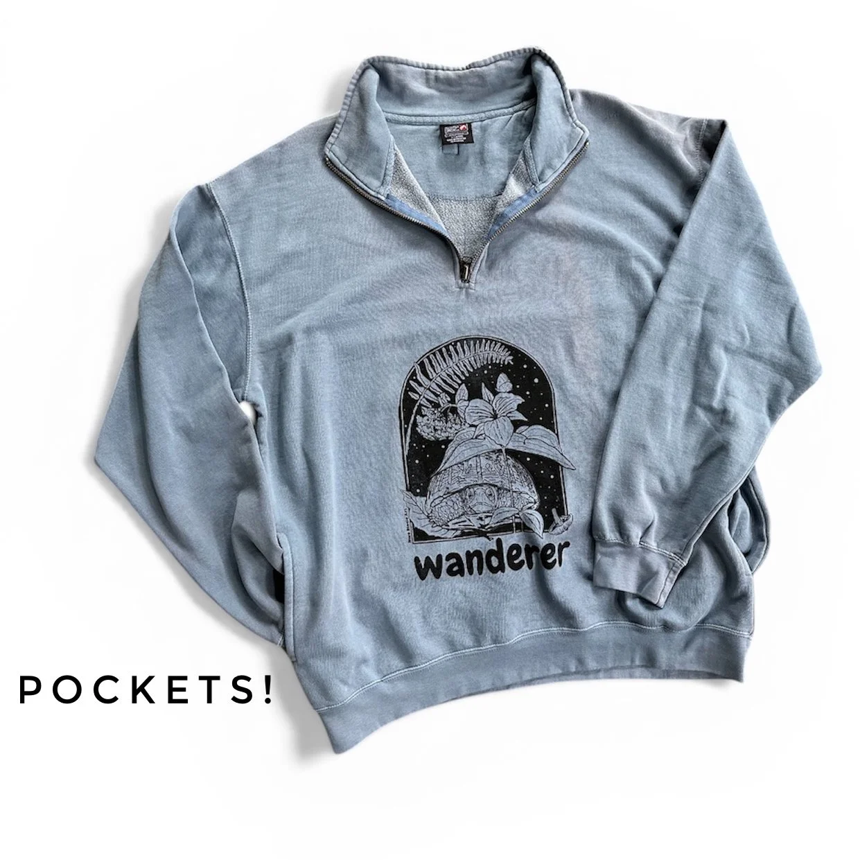 Sweatshirt with pockets screenprinted with a box turtle, trillium, fern, and bluebells with text saying "wanderer"