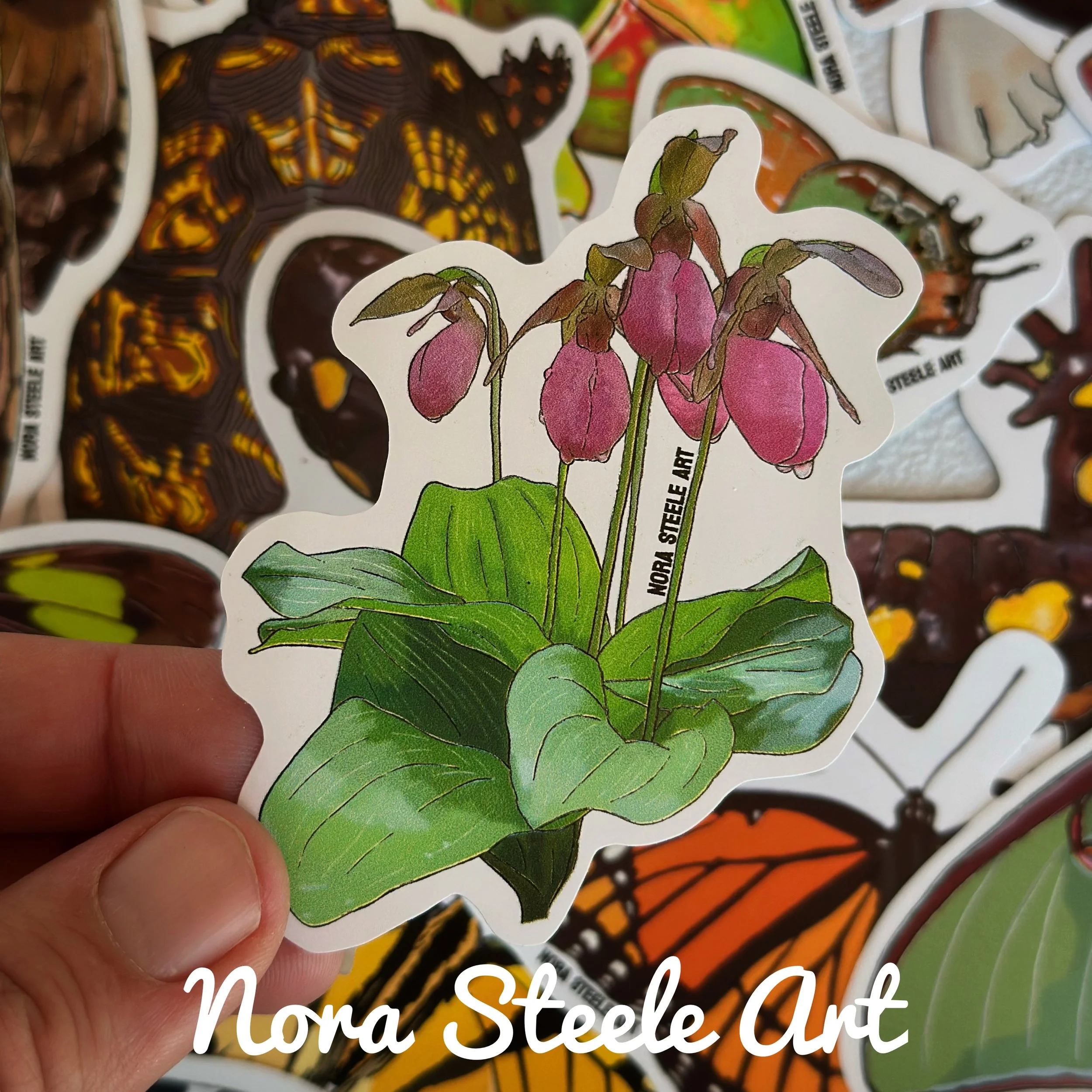 Pink lady's slipper flower sticker bouquet held above a pile of other stickers