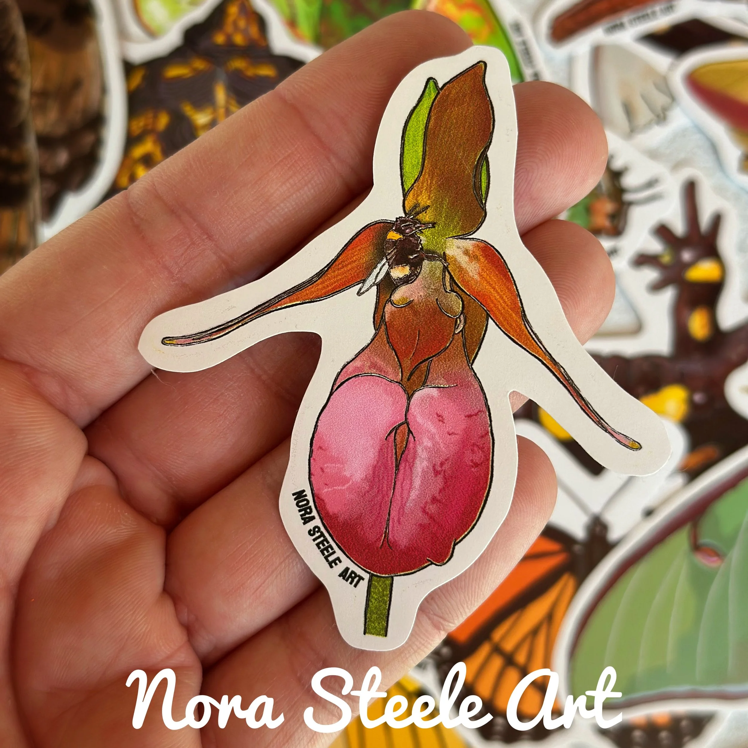 Pink ladys slipper flower sticker held above a pile of other stickers