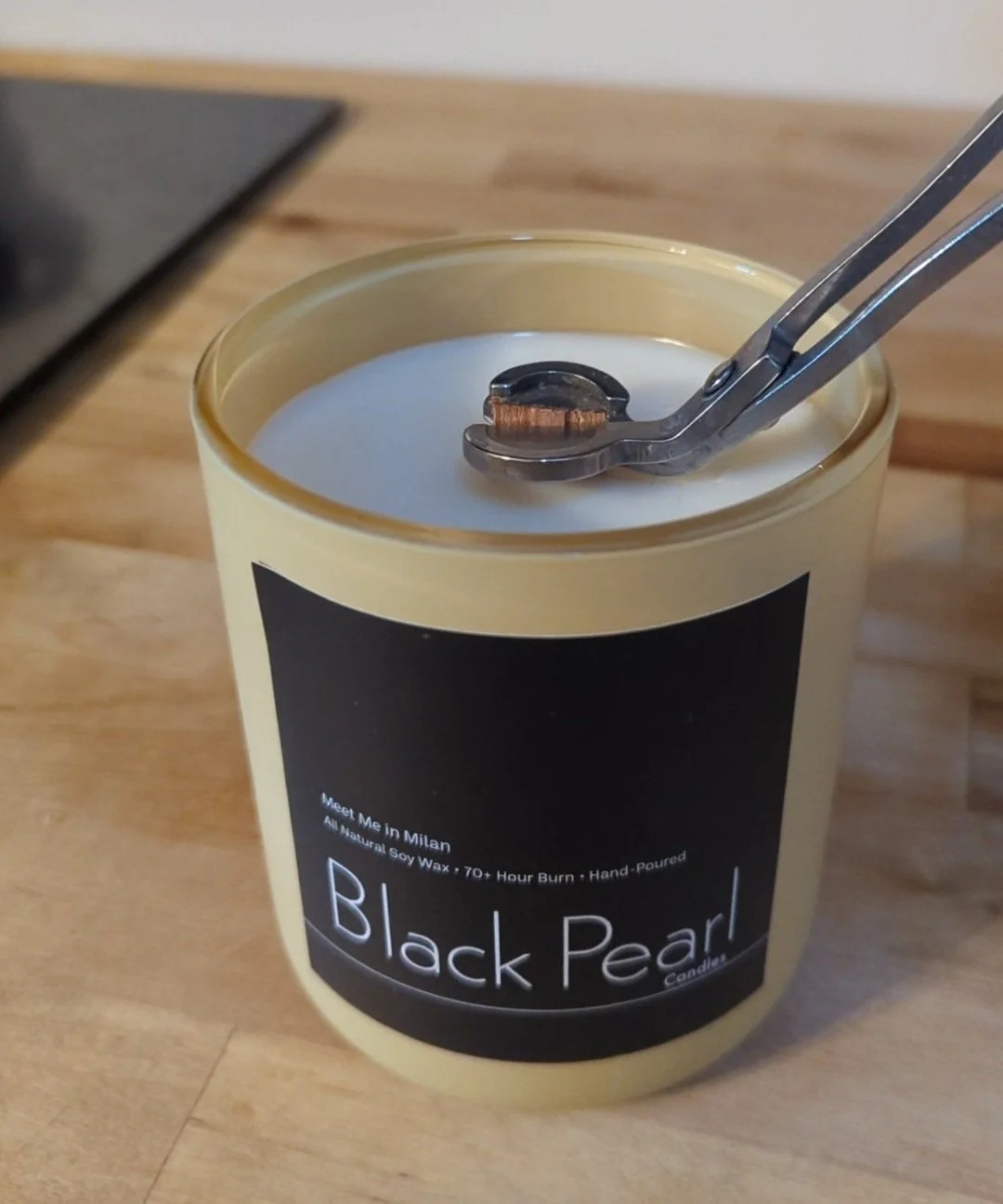 Using a wick trimmer to trim a wood wick soy candle