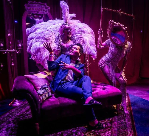 Guest posing with feathered showgirls at Marriott's Tales of the Cocktail pop-up