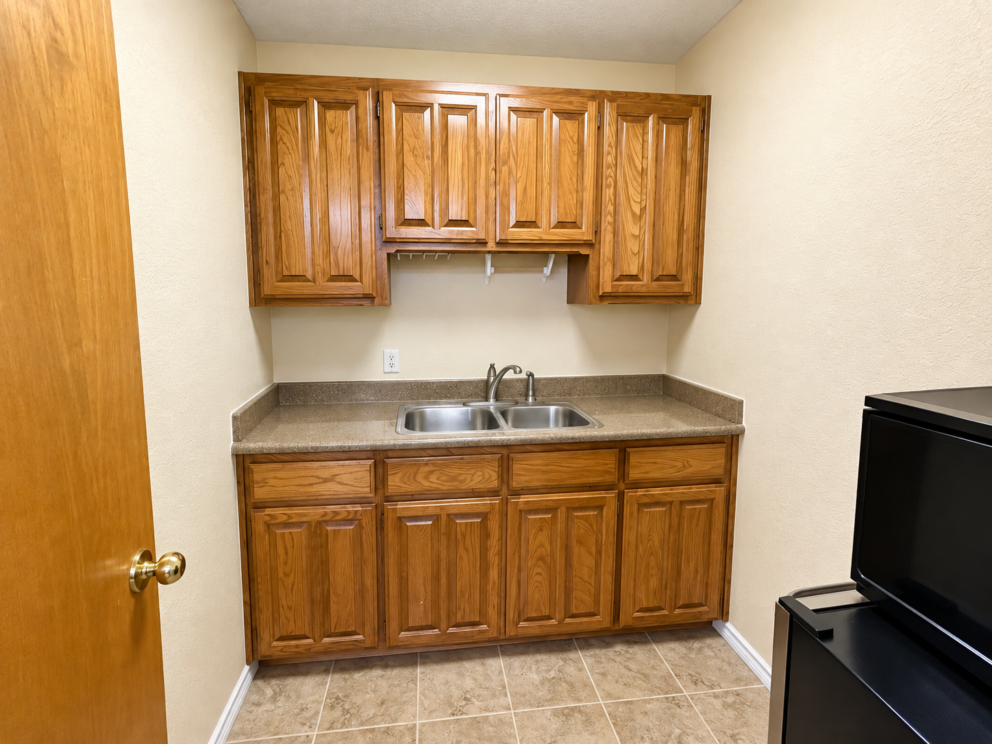 Interior kitchenette with oak cabinets, countertop, and sink at AFT Commercial's 313 Harwood Road office property in Bedford, TX.