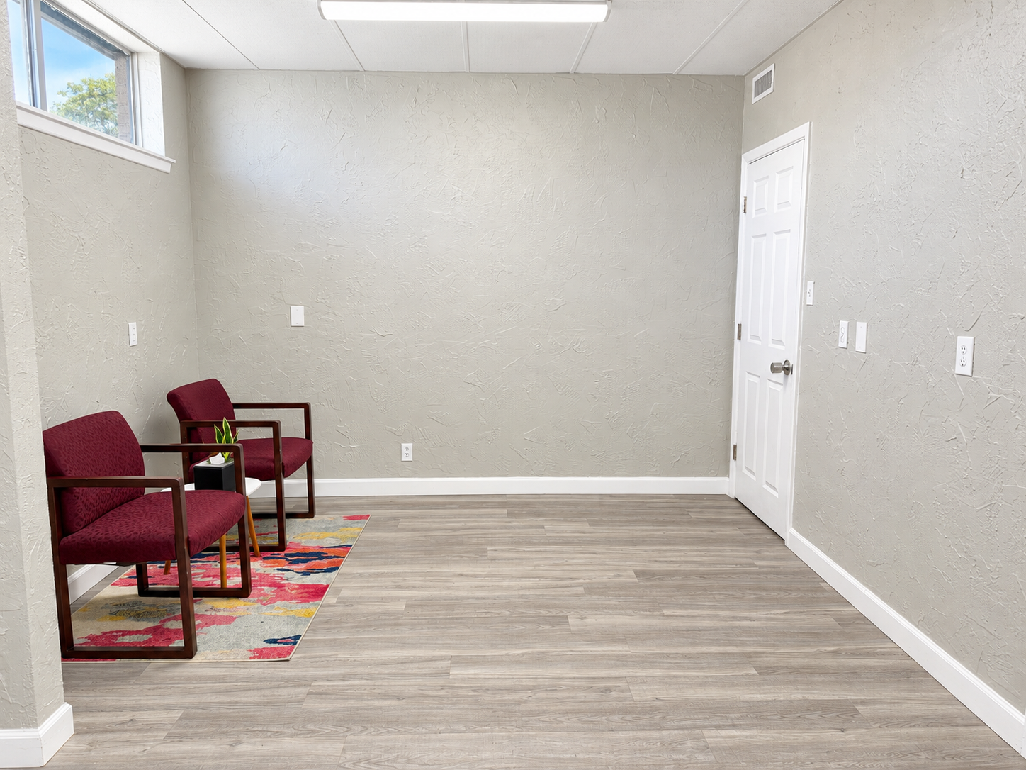 Private office with two red chairs, wood-look flooring, neutral walls, and natural light at 112 W. Pipeline Road in Hurst, Texas.