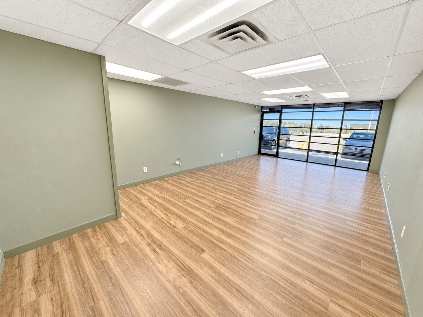 Spacious open office interior with wood-look flooring, white walls, and large windows at 6320 Brentwood Stair Road in Fort Worth, Texas.