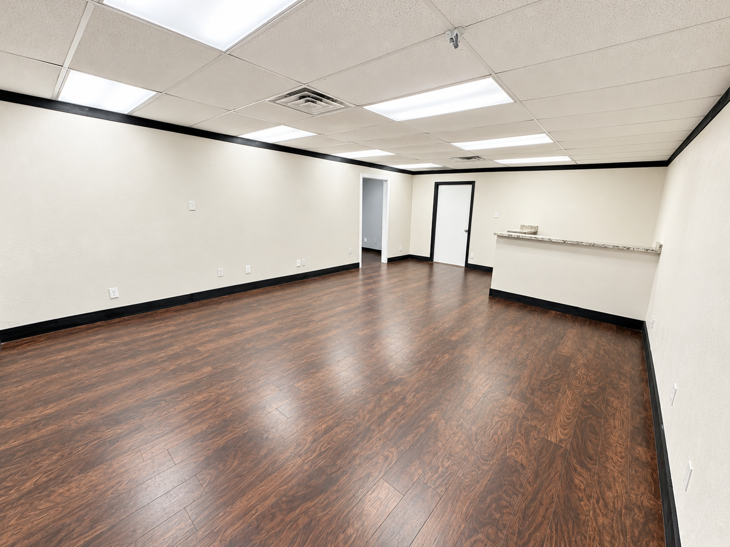 Spacious open office with wood-look flooring, white walls, and overhead lighting at 720 W. Harwood Road in Hurst, Texas.