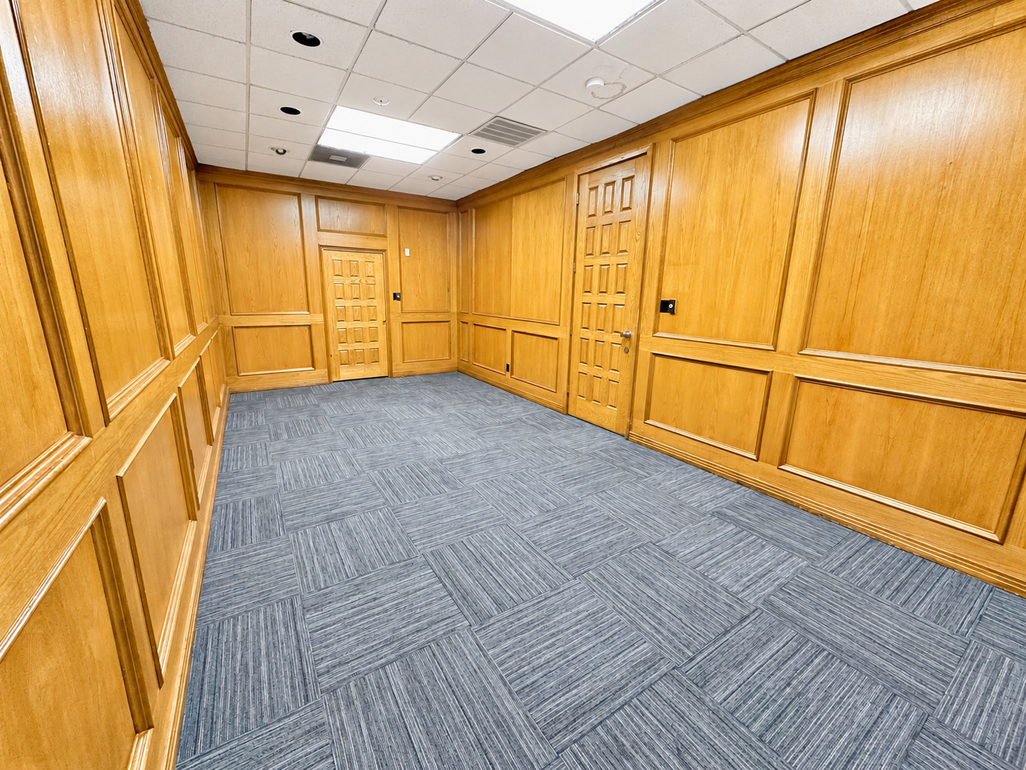Commercial office building hallway with wood-paneled walls, carpeted flooring, and interior doors at 6320 Brentwood Stair Road in Fort Worth, Texas.