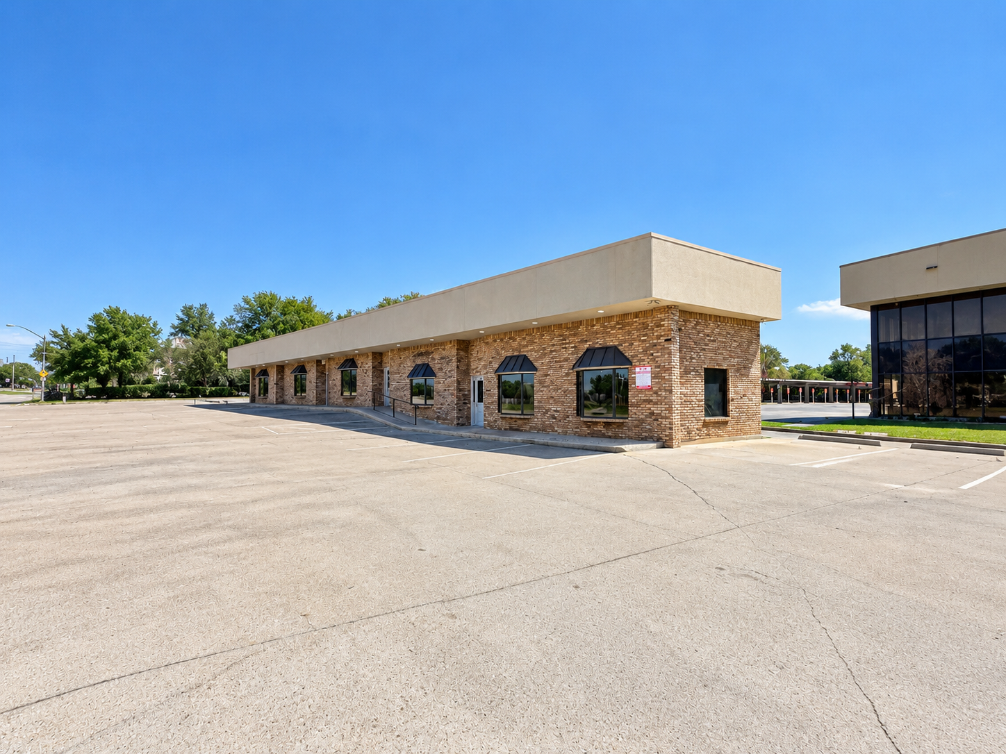 Exterior of commercial office building at 6401 Brentwood Stair Road in Fort Worth, Texas, featuring brick construction, landscaped surroundings, and parking area.