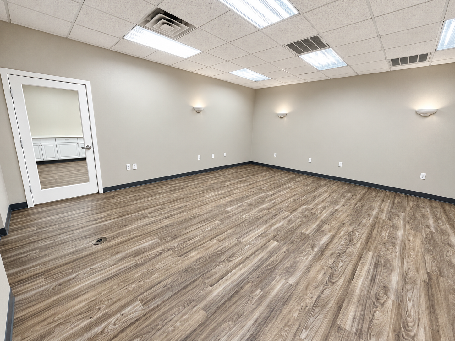 Spacious open office interior with wood-look flooring, neutral walls, and overhead lighting at 425 Westpark Way in Euless, TX.