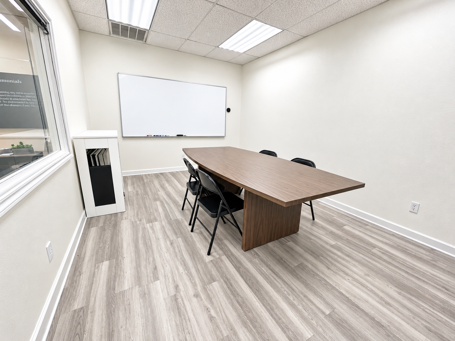Professional office space with wood-look flooring, a table, chairs, and natural light at 405 Airport Freeway in Bedford, Texas.