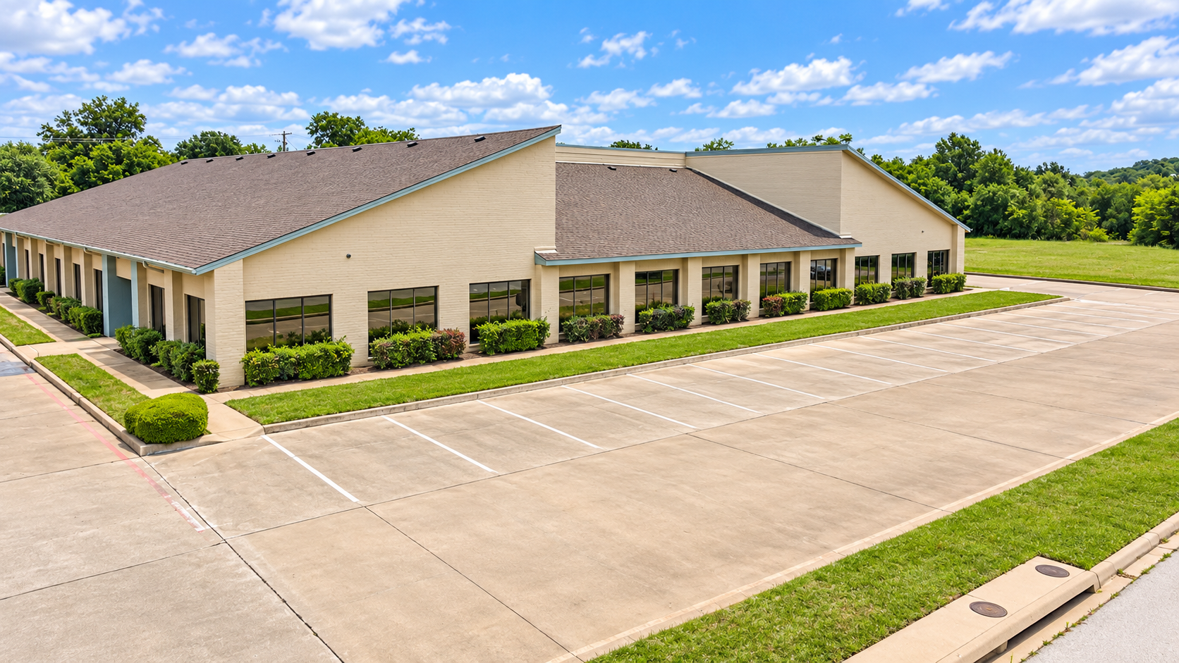 Exterior of commercial office building at 6825 Manhattan Boulevard in Fort Worth, Texas, featuring a brick facade, landscaped grounds, and parking area.