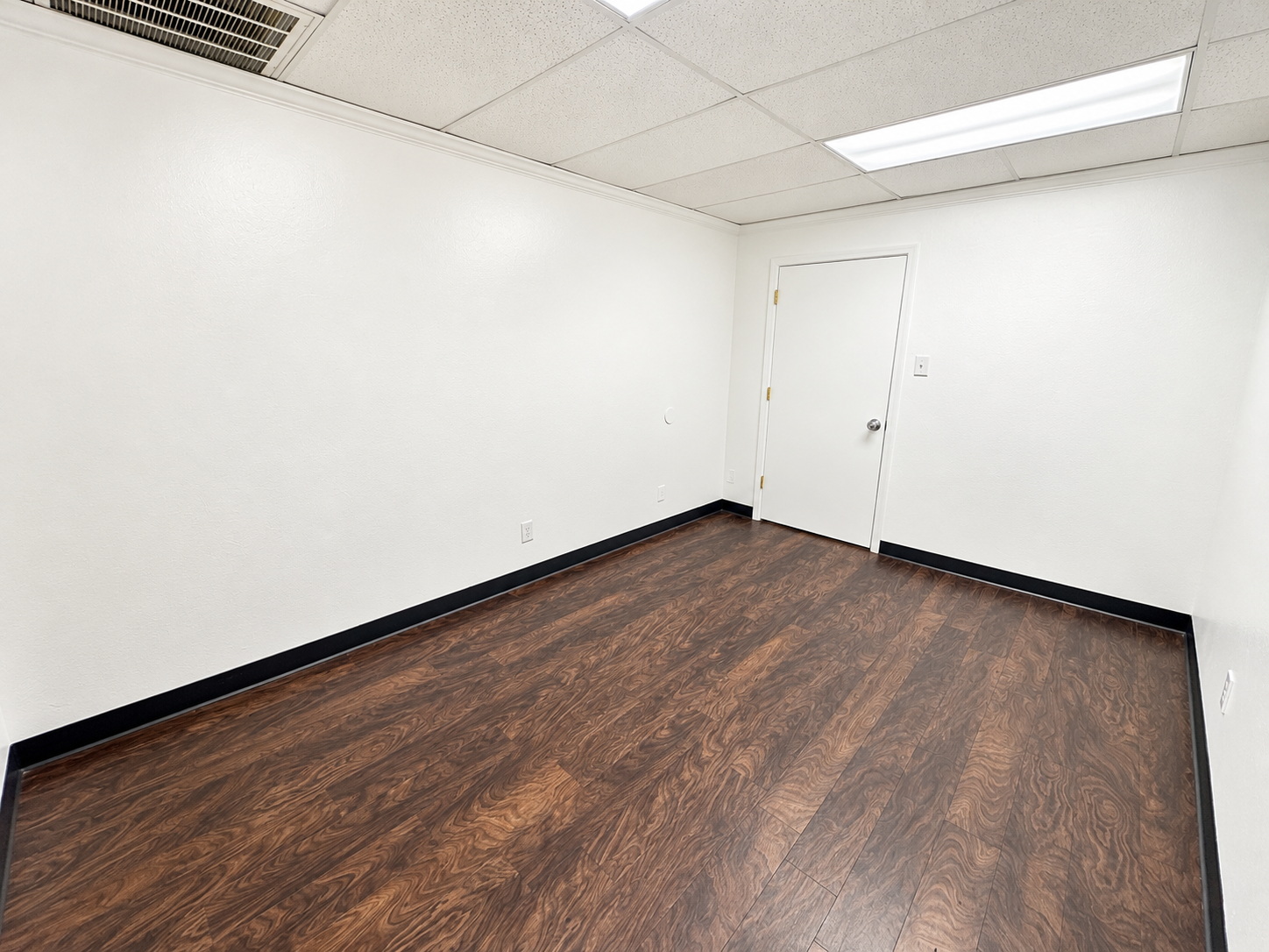 Unfurnished private office with wood-look flooring, white walls, and overhead lighting at 720 W. Harwood Road in Hurst, Texas.