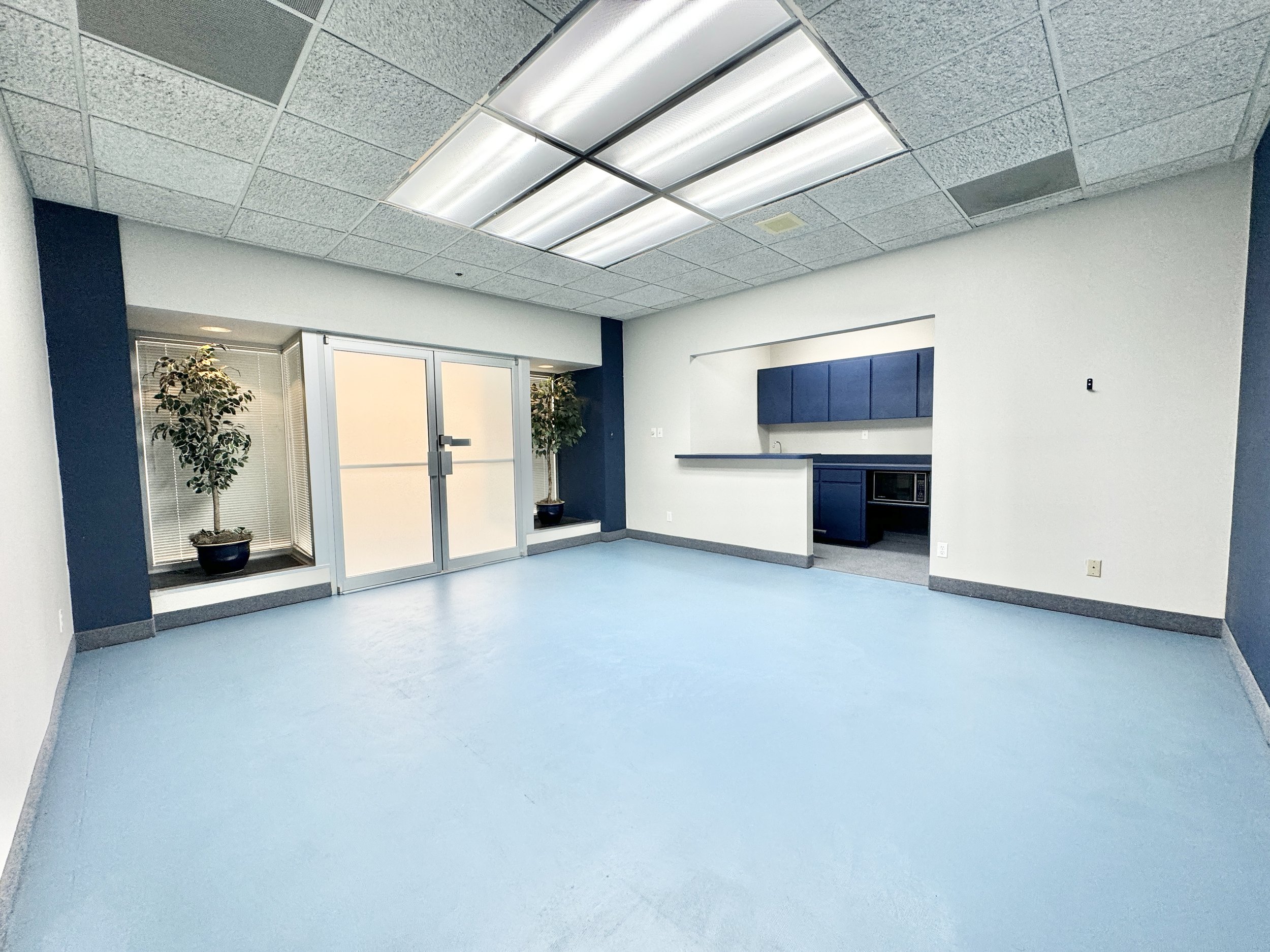 Professional office meeting room with a table, chairs, whiteboard, and overhead lighting at 6850 Manhattan Boulevard in Fort Worth, Texas.