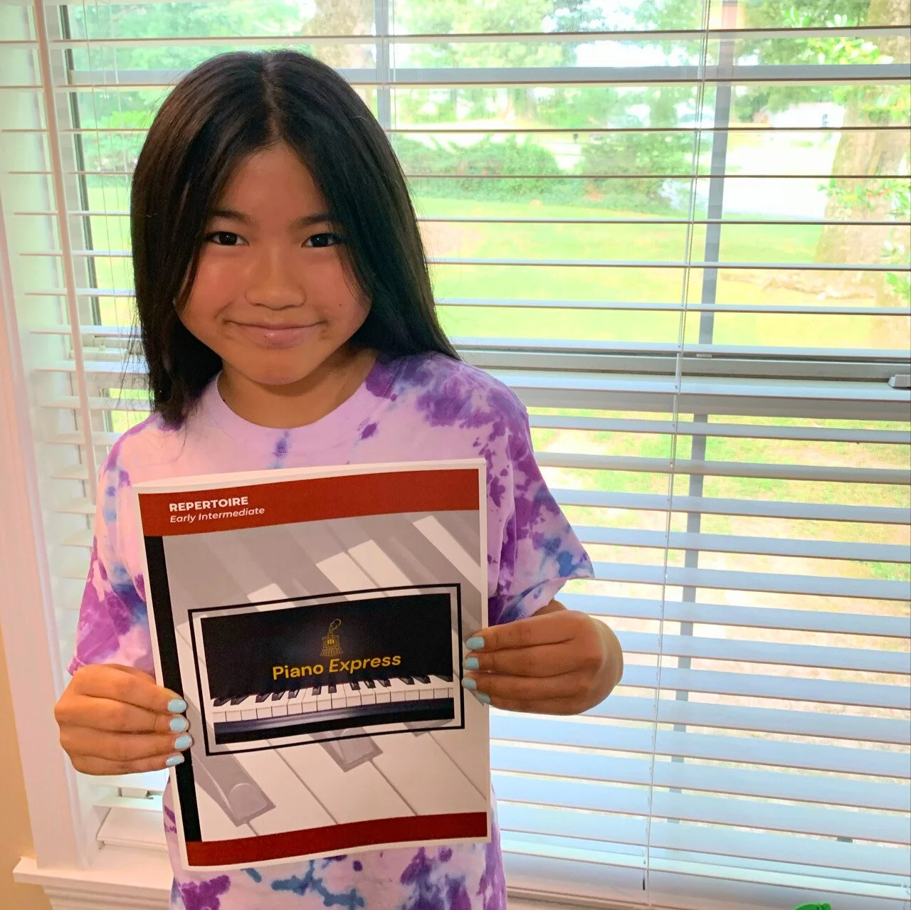 Student smiling and holding up her new Level EIA (Early Intermediate) book.