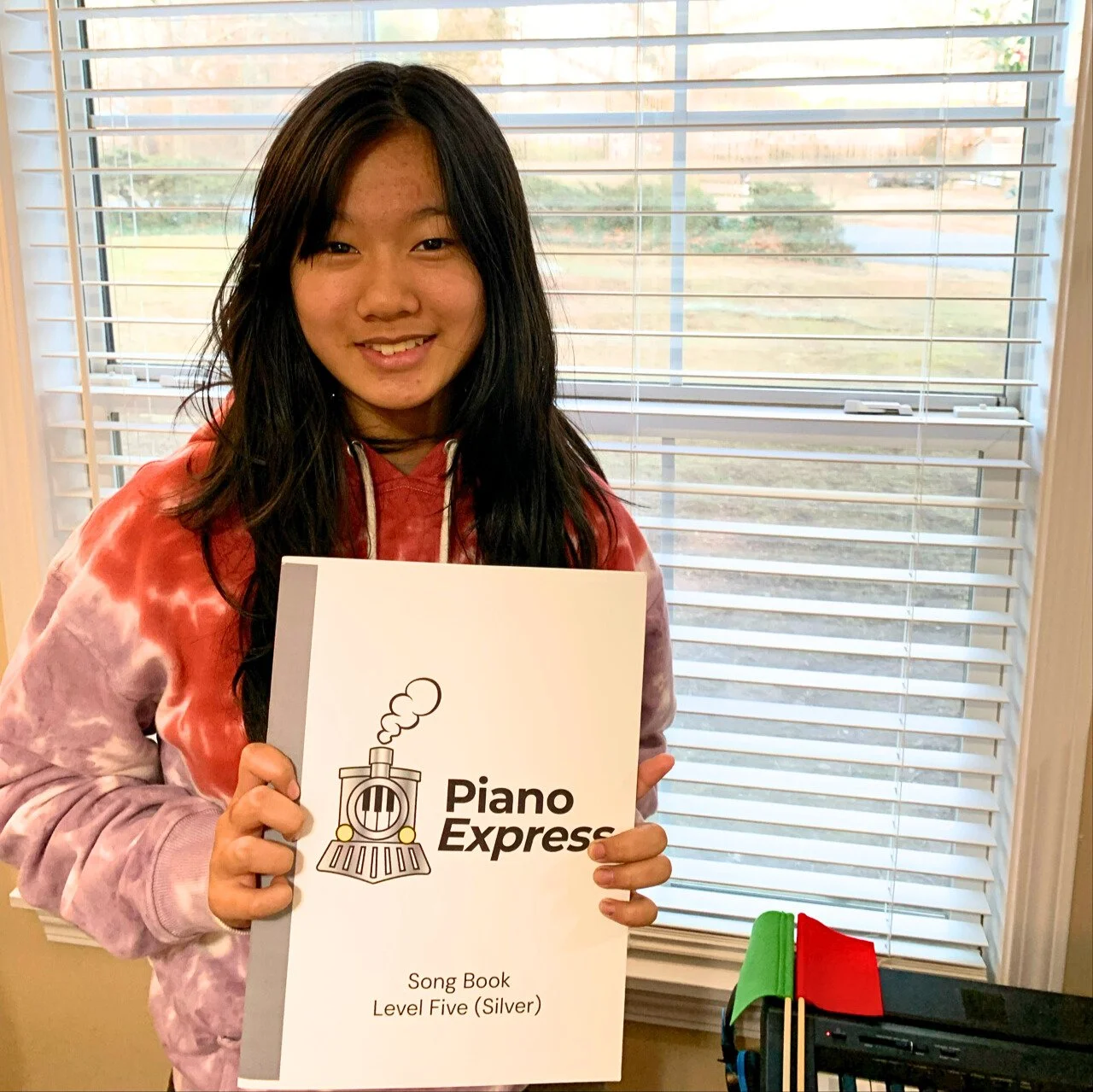 Student smiling and holding up her new Level 5 (Silver) book.