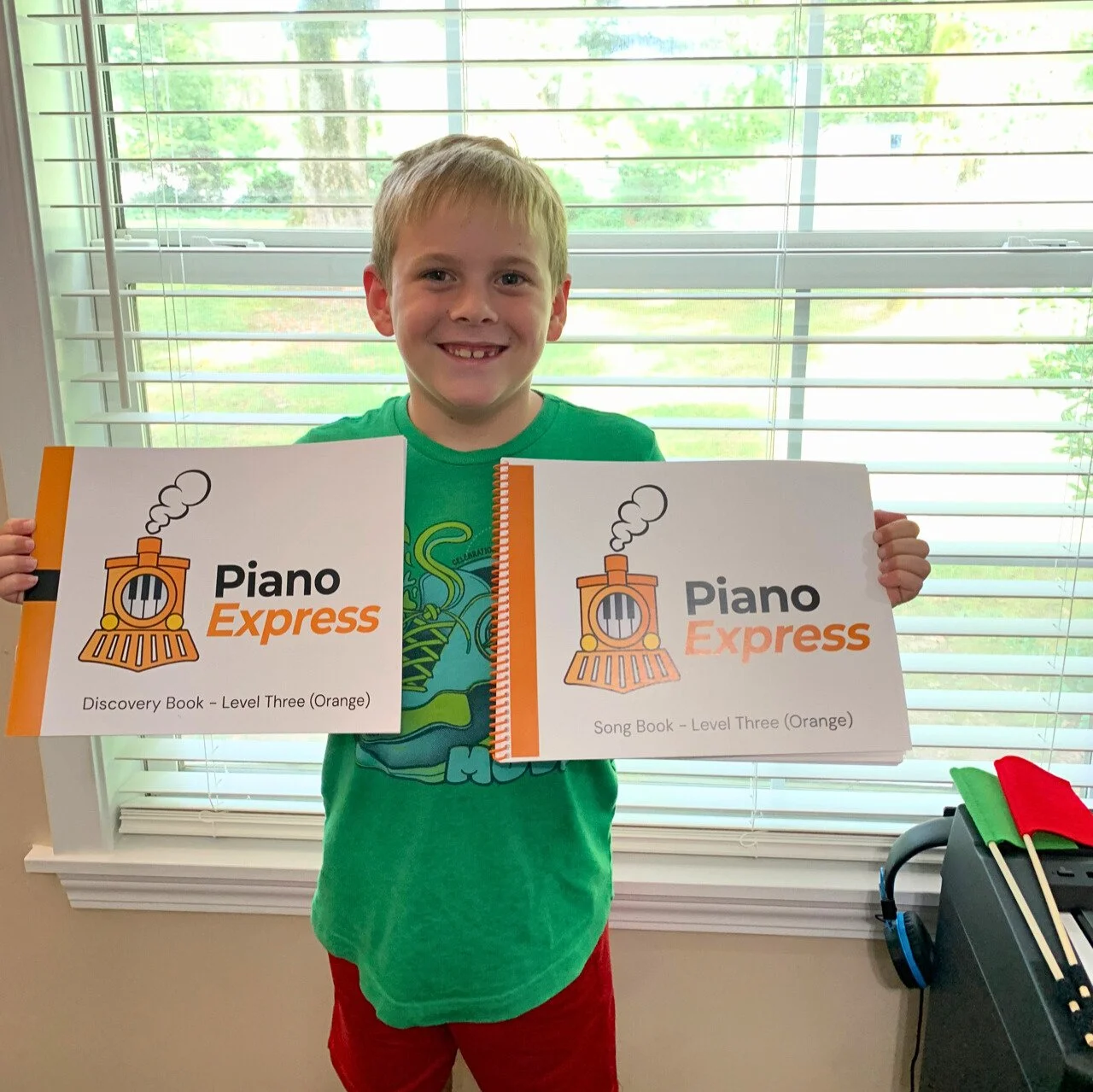 Student smiling and holding up his new Level 3 (Orange) books.