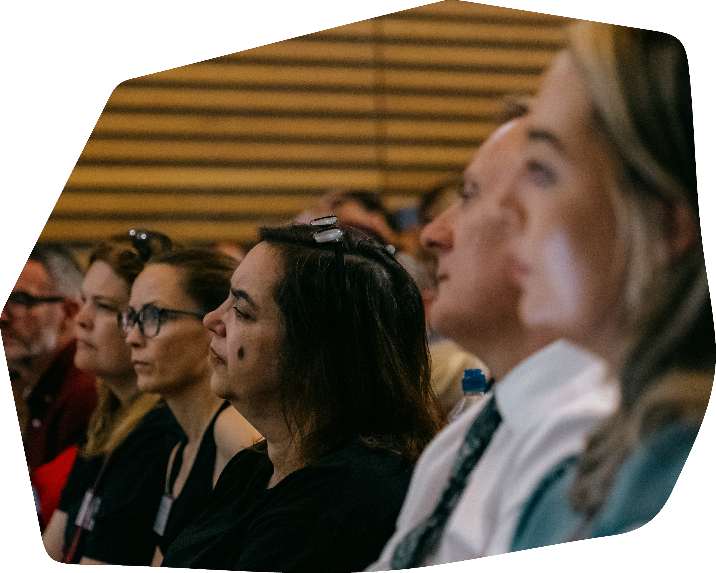 Audience members sitting attentively in a conference or seminar, paying attention to a presentation.