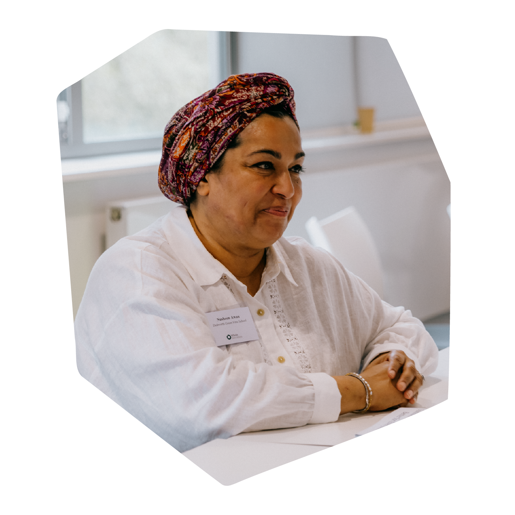People attending a conference or seminar seated at tables in a bright, modern room with large windows and closed blinds.