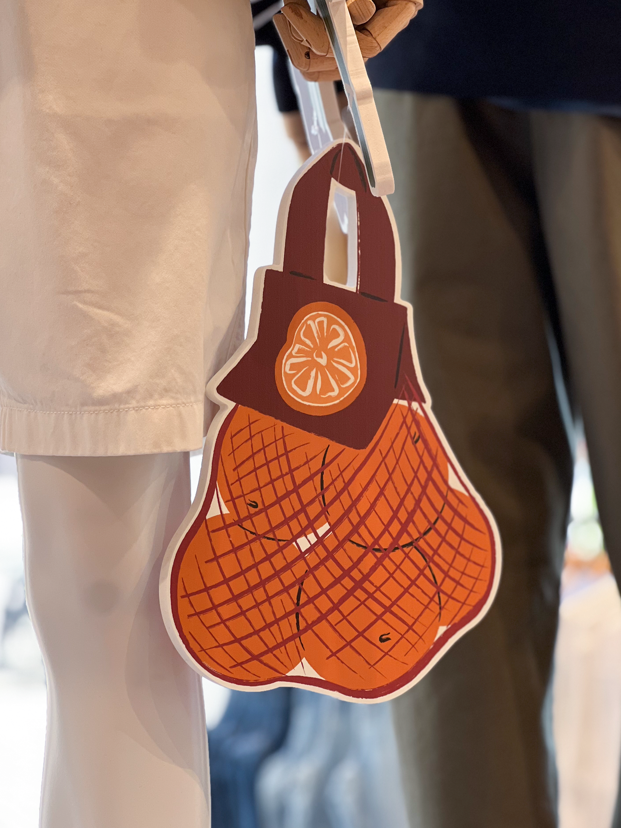 Prop of a net with oranges being held by a mannequin, illustrated by Sandy van Helden for  UNIQLO's Koningsplein’s 2025 seasonal visual merchandising