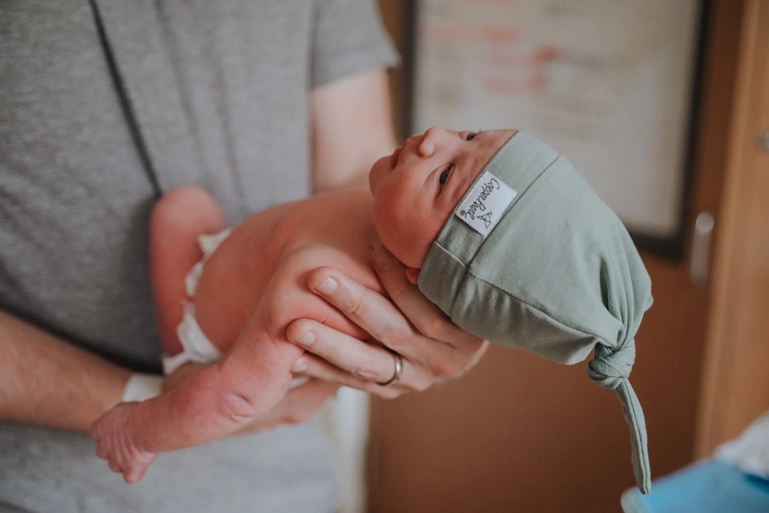 Newborn baby hangs out in dads arms for skin to skin