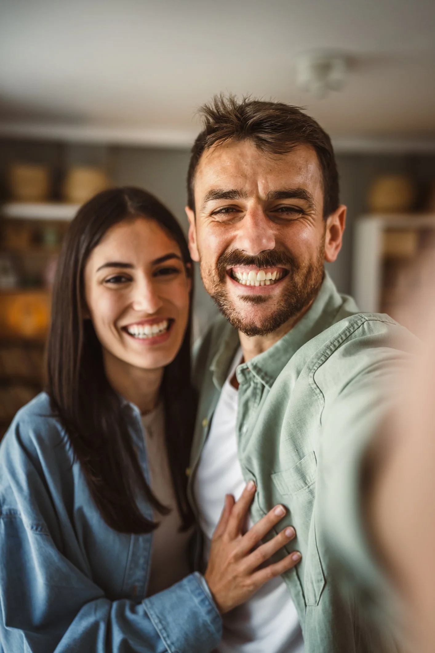 A smiling man and woman taking a selfie together indoors.